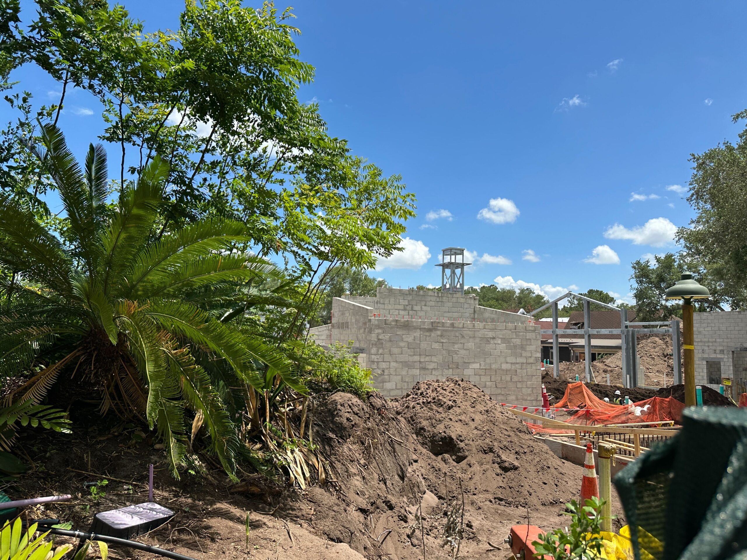 The clock tower that started to go vertical last month is still visible above the green construction walls and is surrounded by cinder block walls.