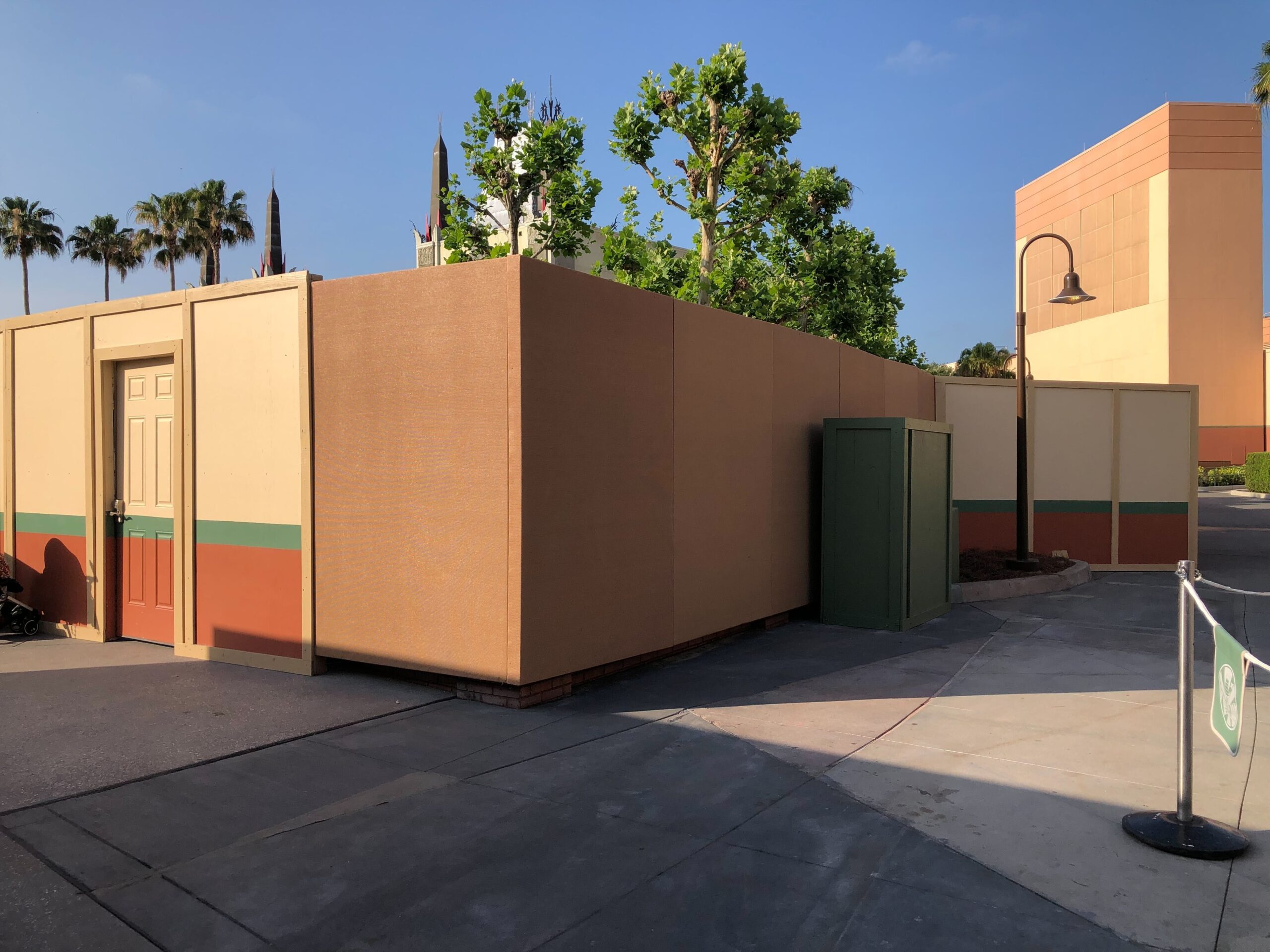 Construction walls in front of the theater have shifted once again. We can now see a brick column below a corner of the walls. In the close-up of concept art below, this column is on the left, framing the courtyard's entrance.