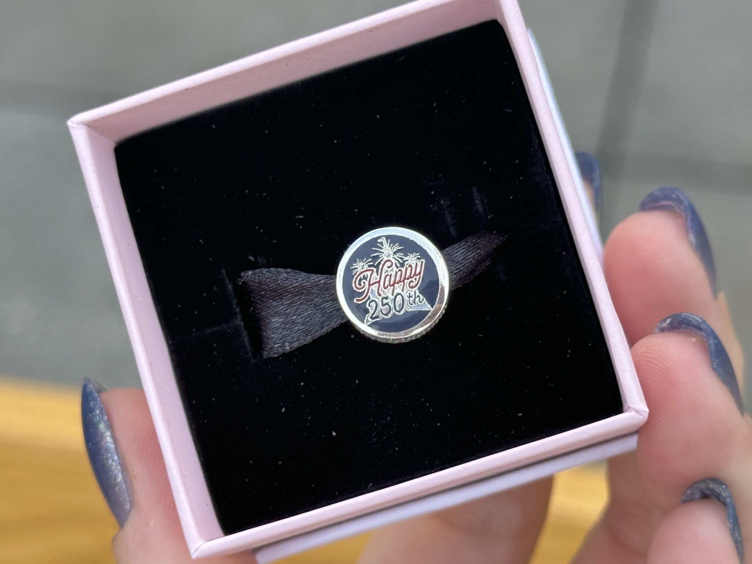 One side of the blue Pandora charm has a Mickey icon with stars on the top half and red and white stripes on the bottom half. On the other side is a star with "Happy 250th" text in front of it.