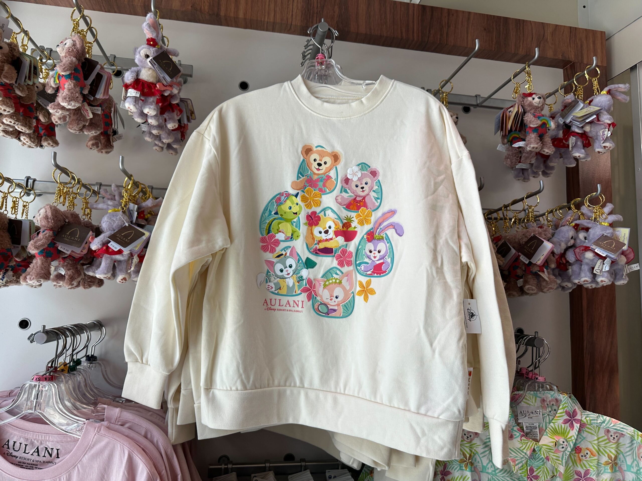 The sweatshirt is off-white with images of Duffy and all his friends on the front. They are in tropical outfits with puffy ink flower details.