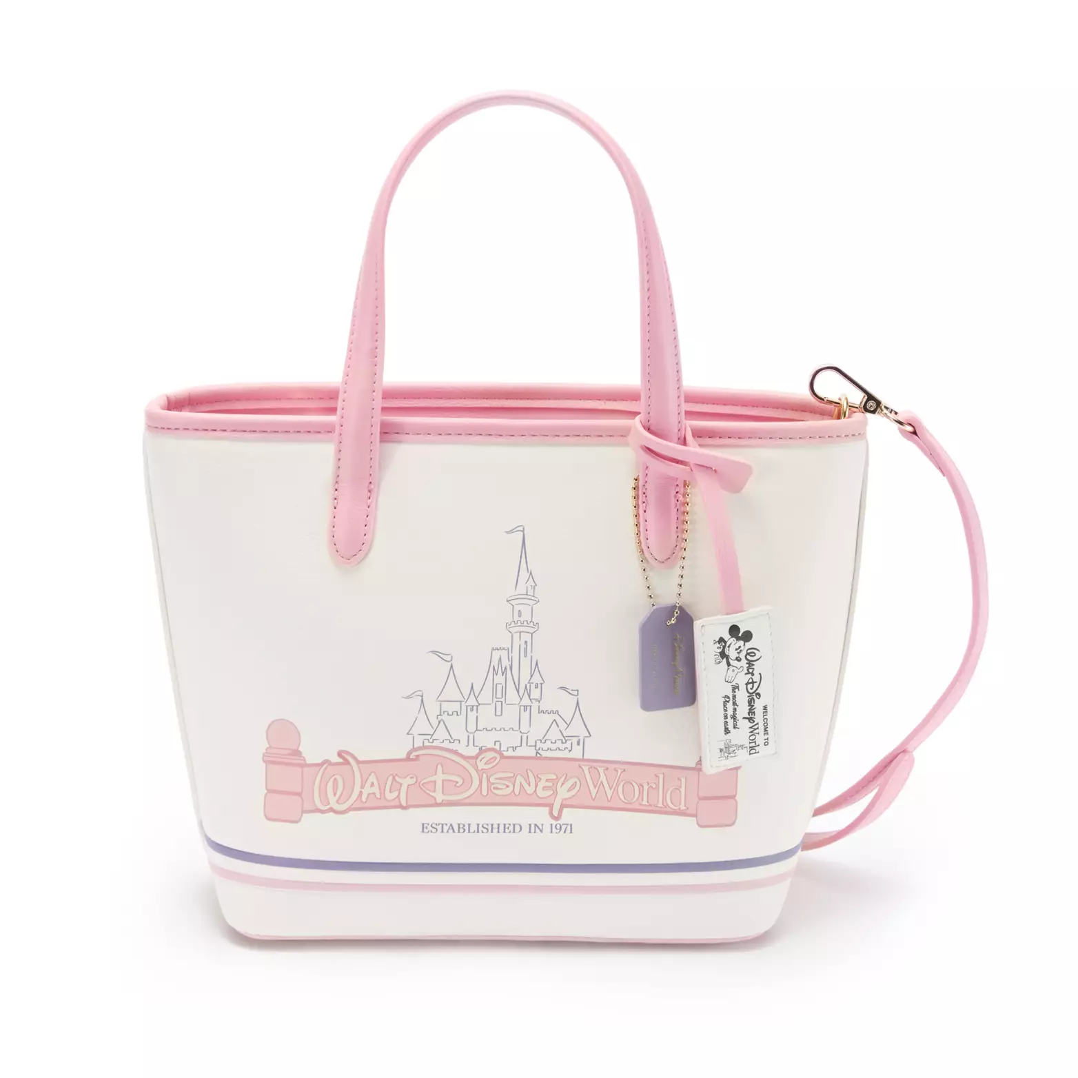 This mini tote bag in a cream and pastel pink aesthetic lends itself to a vintage Walt Disney World theming. There is a retro hangtag attached to the front strap with Mickey in black and white with the Disney World wordmark and the words "Welcome to Walt Disney World the Most Magical Place on Earth." On the front of the bag is an outline of Cinderella Castle with the Disney World marquee in pink above the words "Established in 1971."