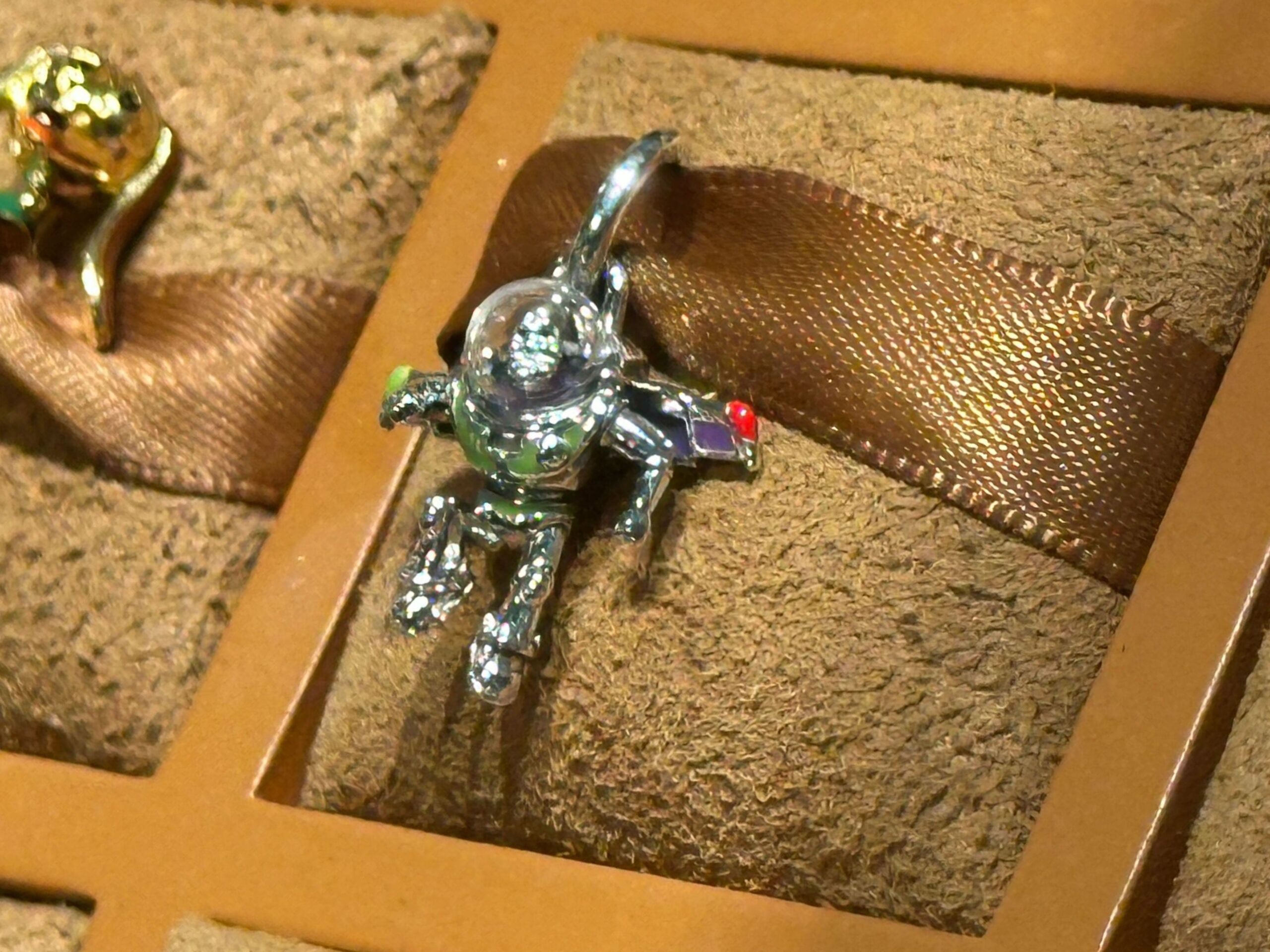 The Buzz charm is sterling silver and enamel with UV resin to add a glossy finish. He's a dangle charm hanging from a silver ring.