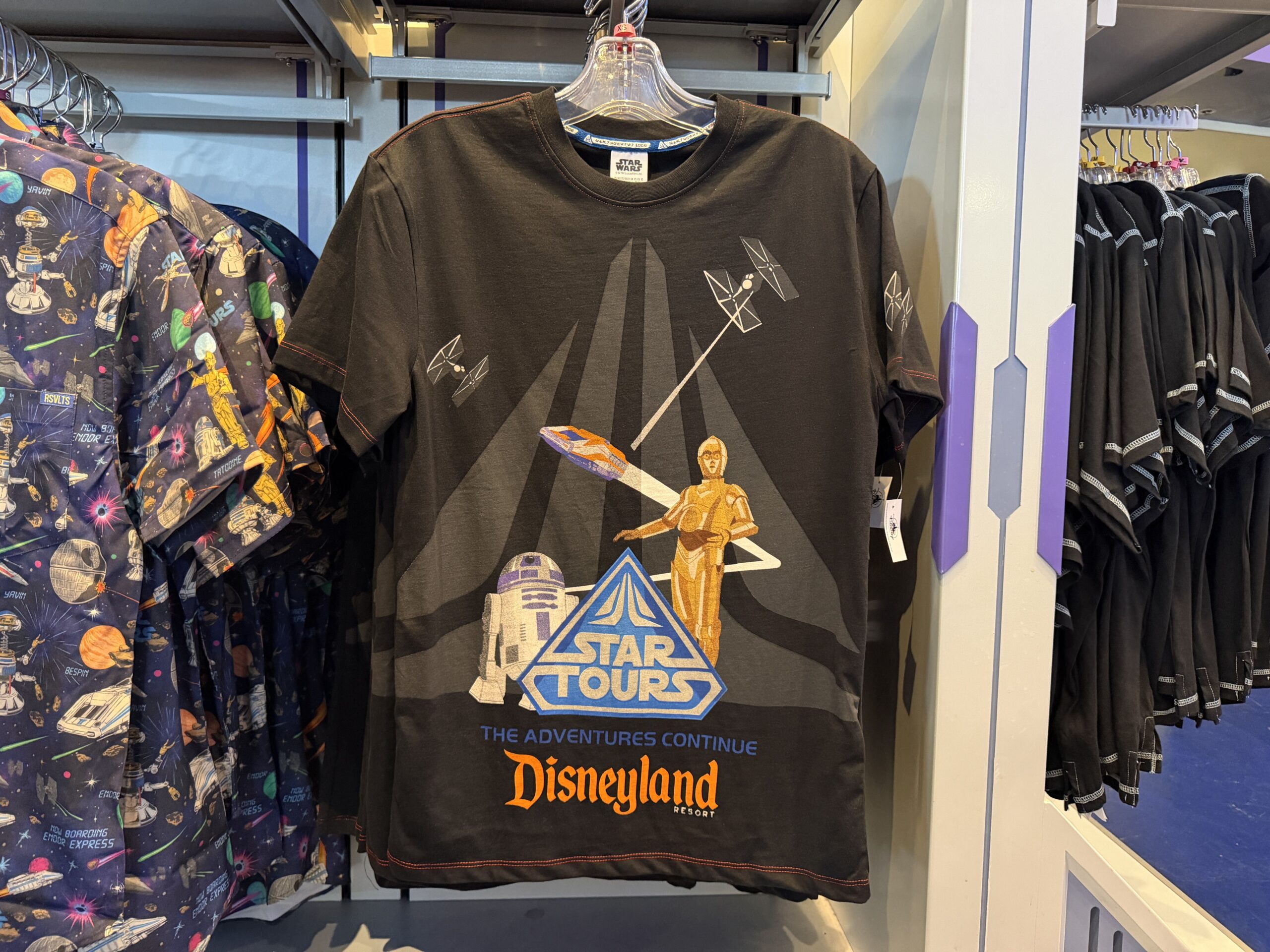 A new wave of Star Wars merchandise has arrived at Disneyland, including several graphic T-shirts, a keychain, and multiple Hasbro Black Series figures inspired by Star Wars: Attack of the Clones, The Mandalorian & Grogu, Star Tours, and more.