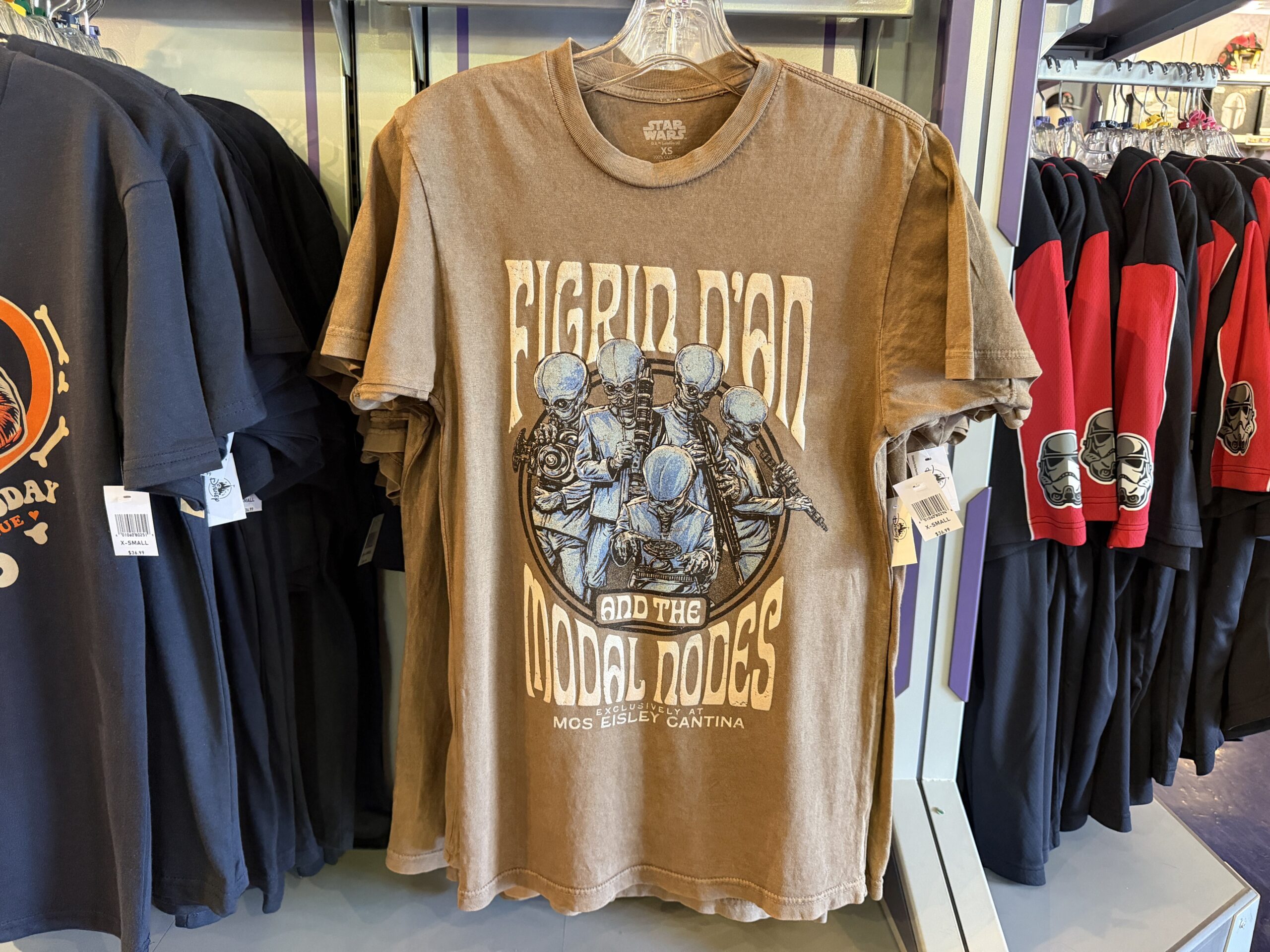 A new wave of Star Wars merchandise has arrived at Disneyland, including several graphic T-shirts, a keychain, and multiple Hasbro Black Series figures inspired by Star Wars: Attack of the Clones, The Mandalorian & Grogu, Star Tours, and more.