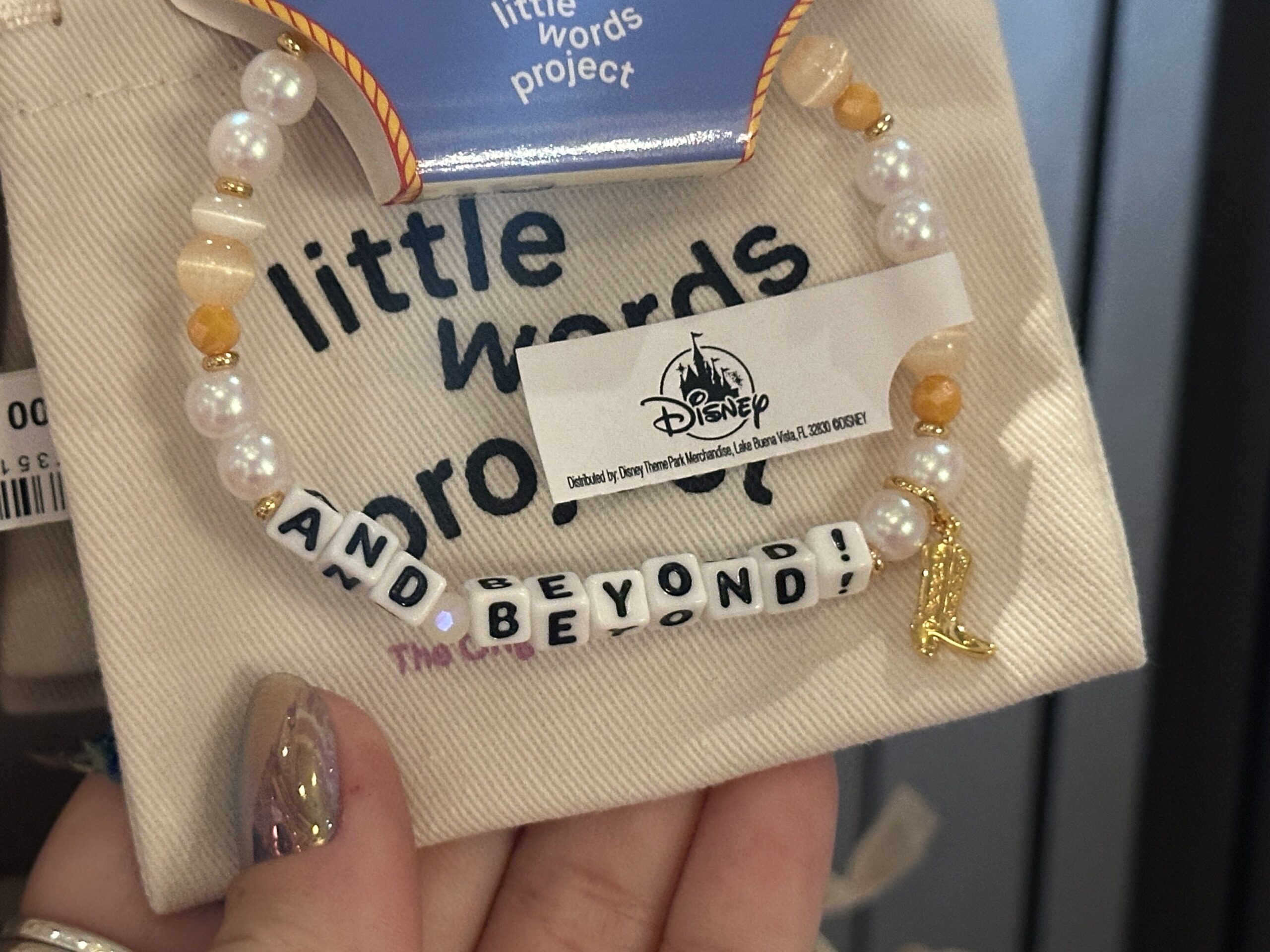 The latter half of Lightyear's catchphrase is featured on the next bracelet, reading "And Beyond!" The decorative beads include pearly white and orange tones with a charm of Woody’s boot.