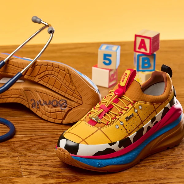 The Woody shoe's styling is based on the toy's famous costume. The top part is yellow with red windowpane lines and matching laces. That's followed by stripes of black and white cow print, red, and blue with a brown sole. Bonnie's name is on the bottom.