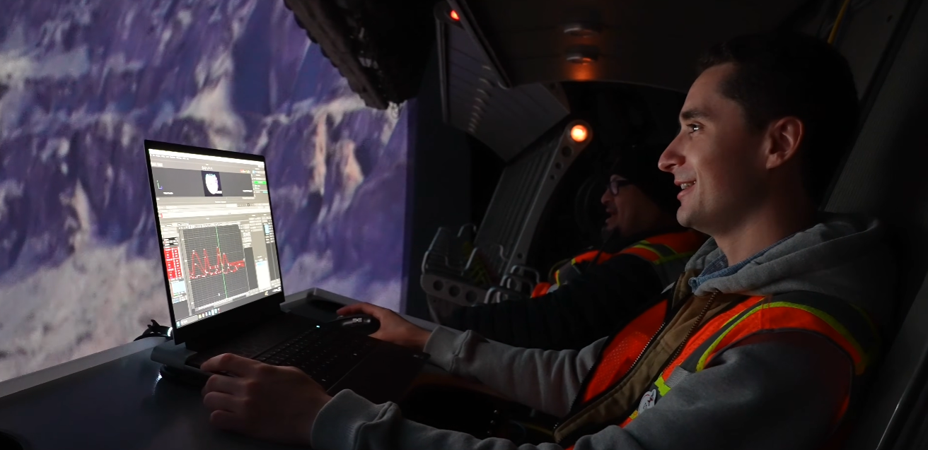 Cast member working on a laptop in front of the Soarin' Across America ride screen.