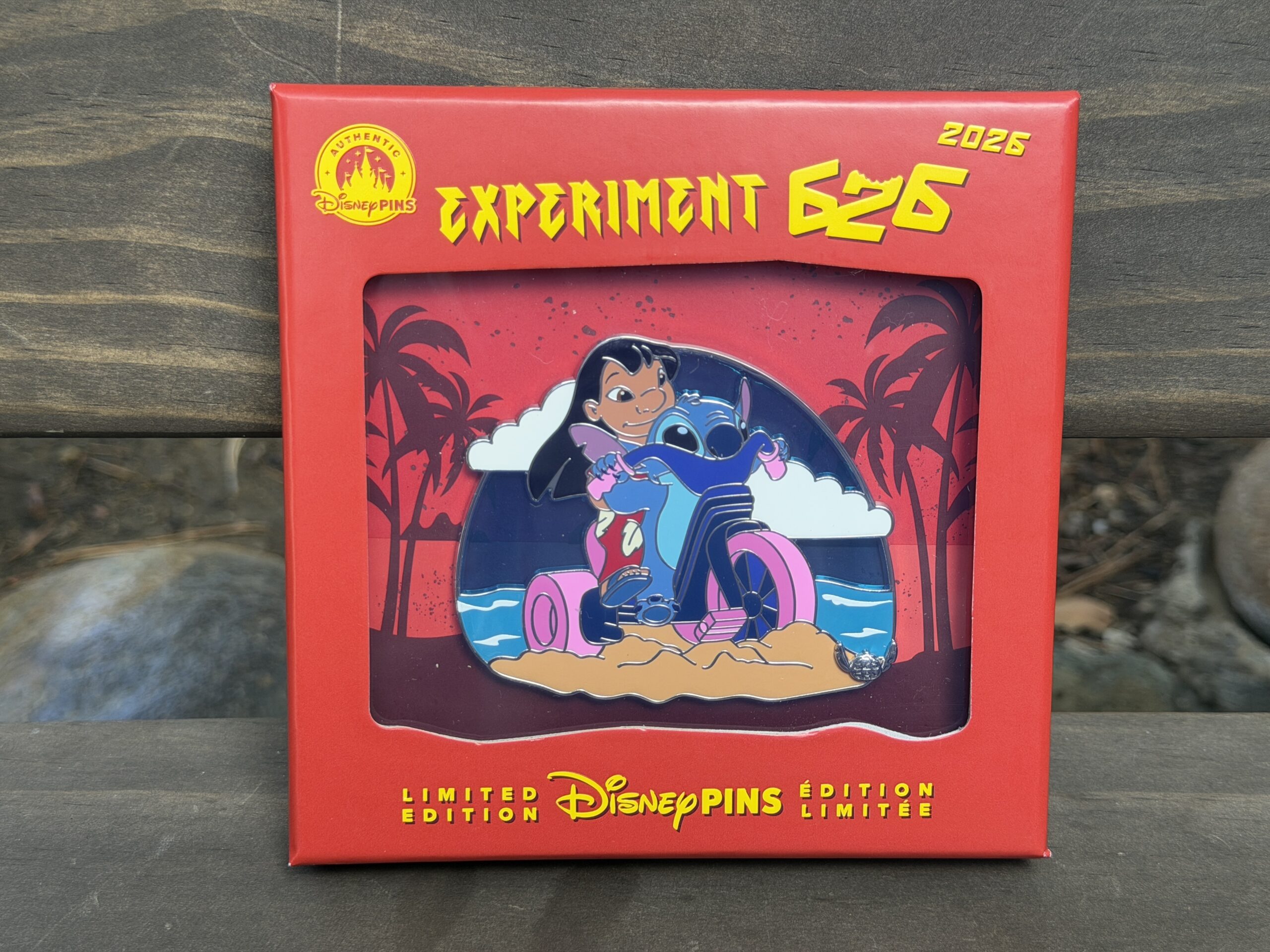 The mini jumbo features Lilo and Stitch and her tricycle with the ocean behind them. A small silvertone Stitch-shaped 626 Day element is in the lower corner.
