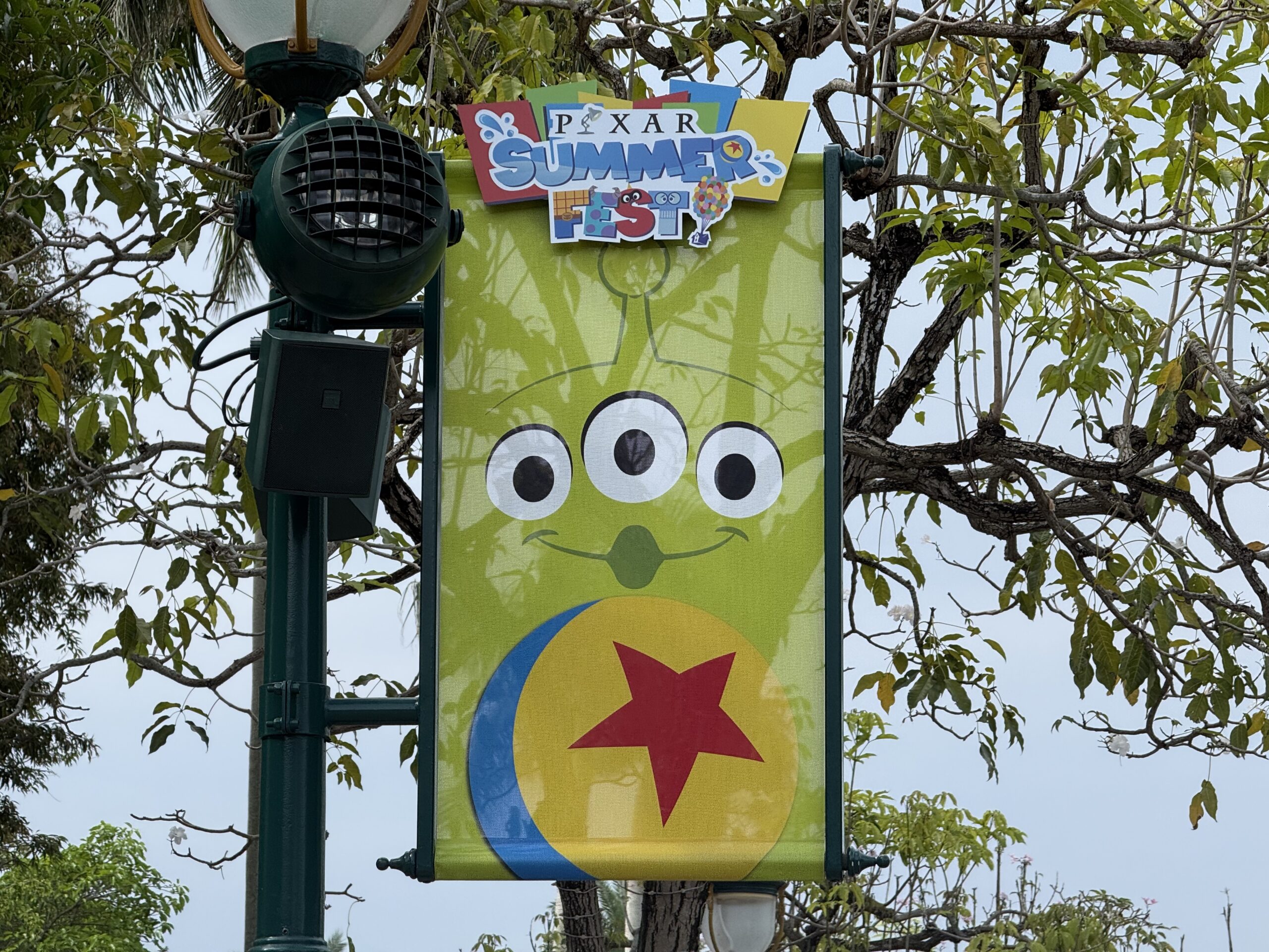 The walkway to the park entrance is lined with banners featuring Pixar characters and the Pixar Summer Fest logo.