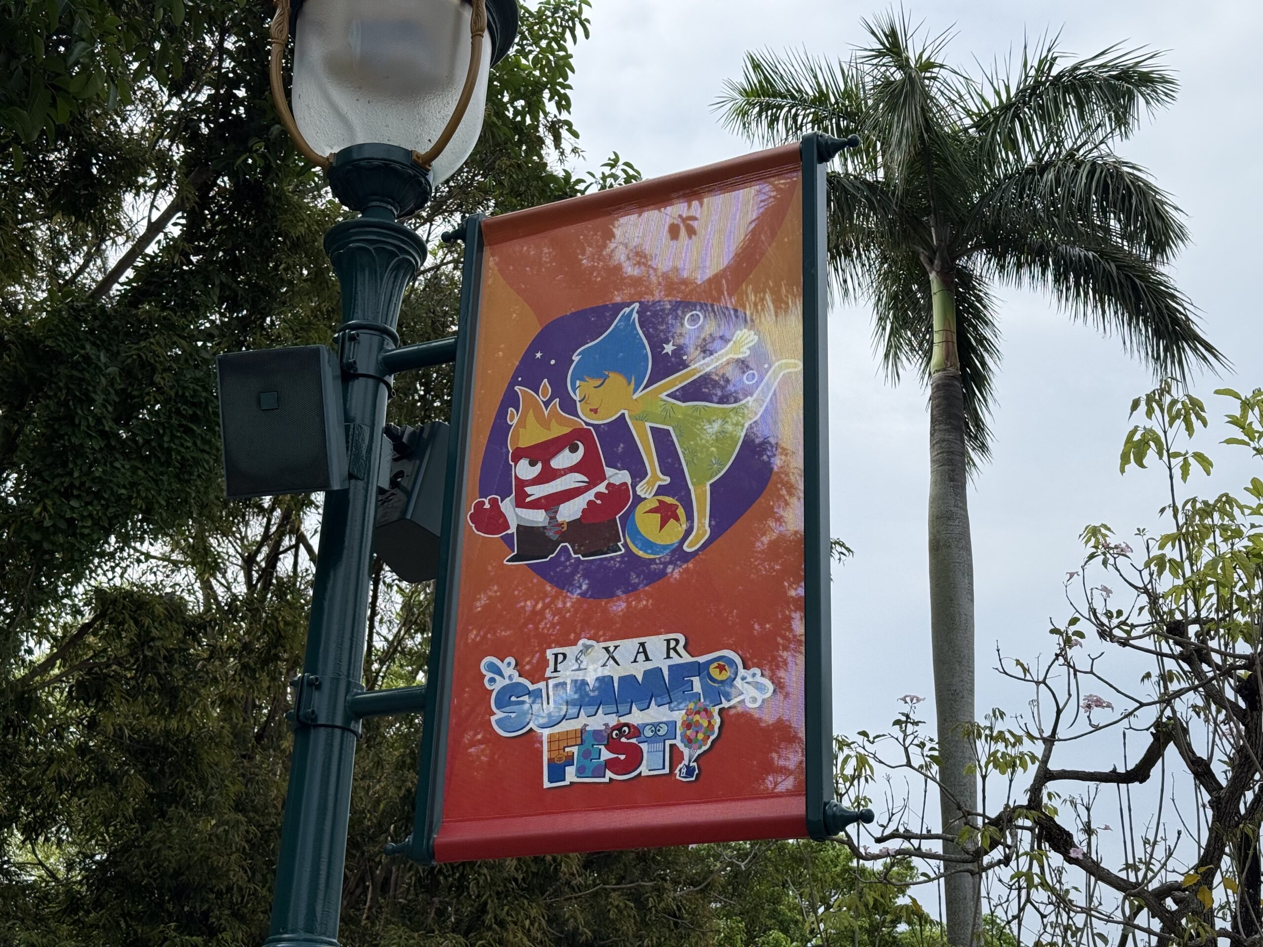 The walkway to the park entrance is lined with banners featuring Pixar characters and the Pixar Summer Fest logo.