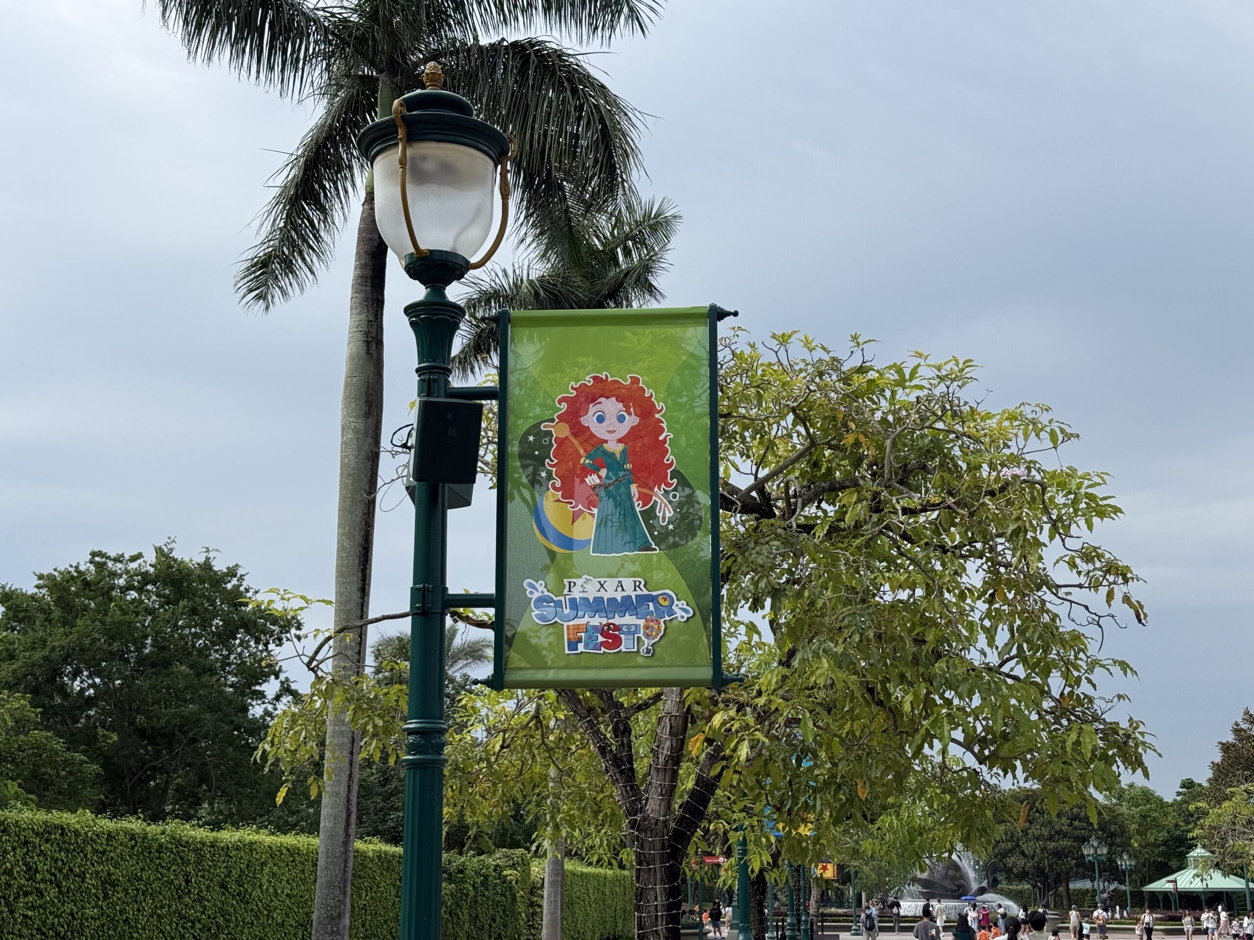 The walkway to the park entrance is lined with banners featuring Pixar characters and the Pixar Summer Fest logo.