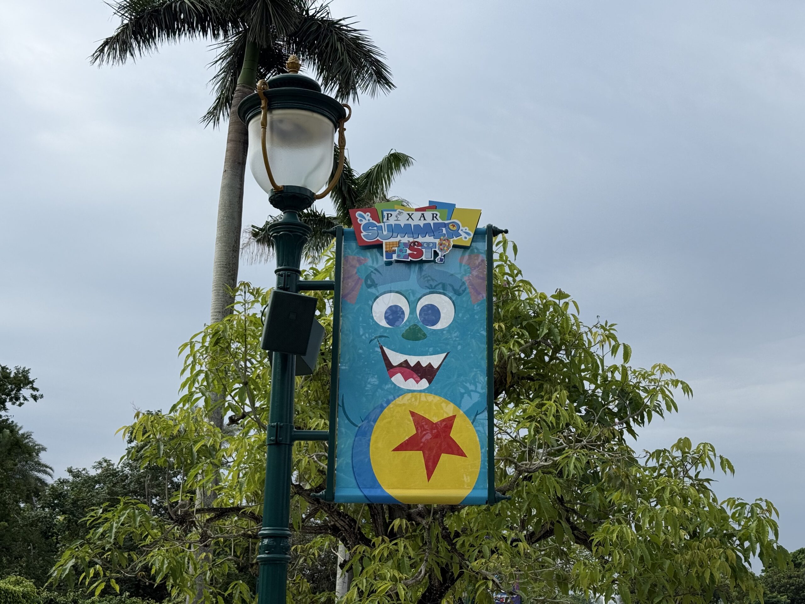 The walkway to the park entrance is lined with banners featuring Pixar characters and the Pixar Summer Fest logo.