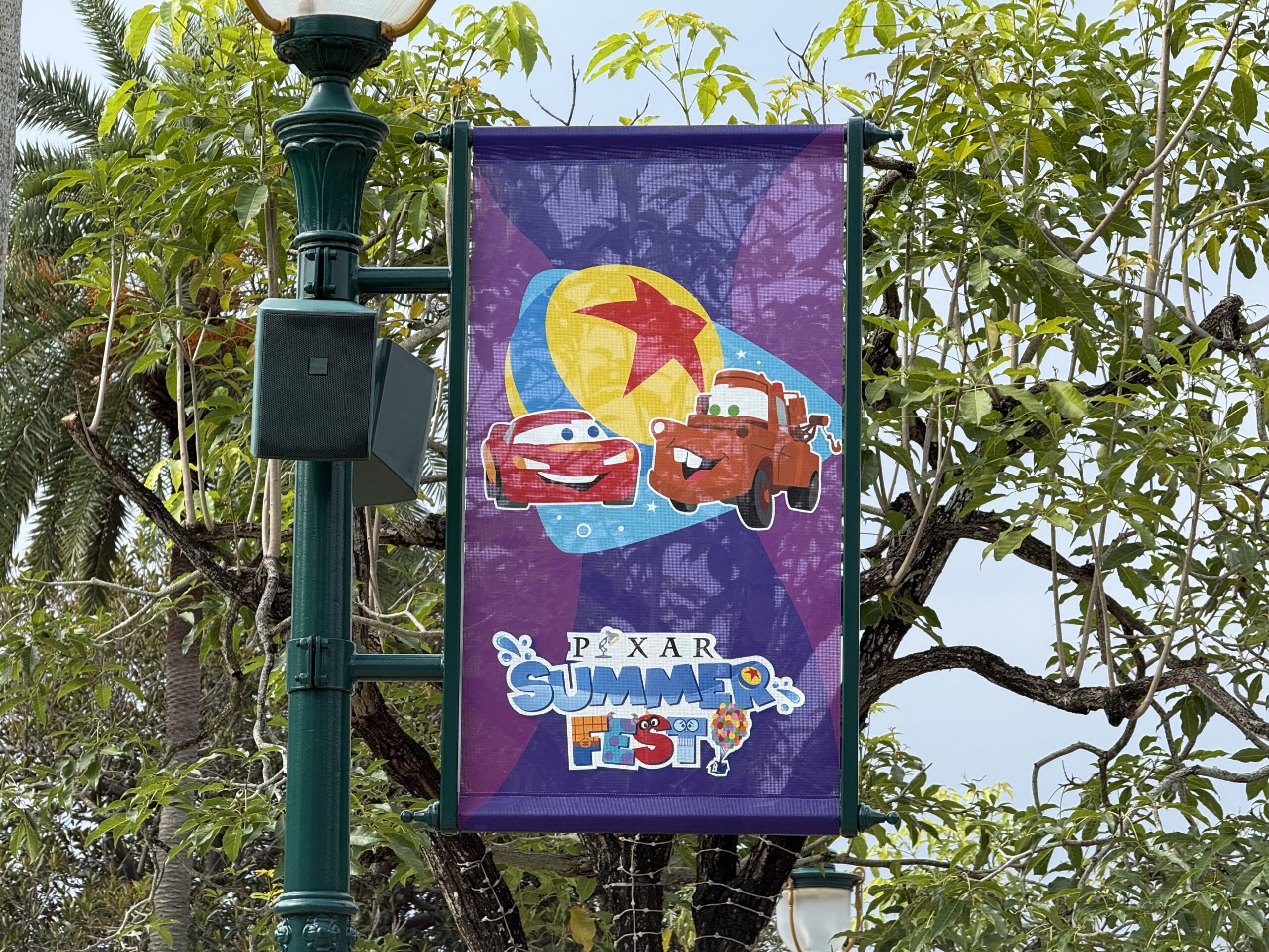 The walkway to the park entrance is lined with banners featuring Pixar characters and the Pixar Summer Fest logo.
