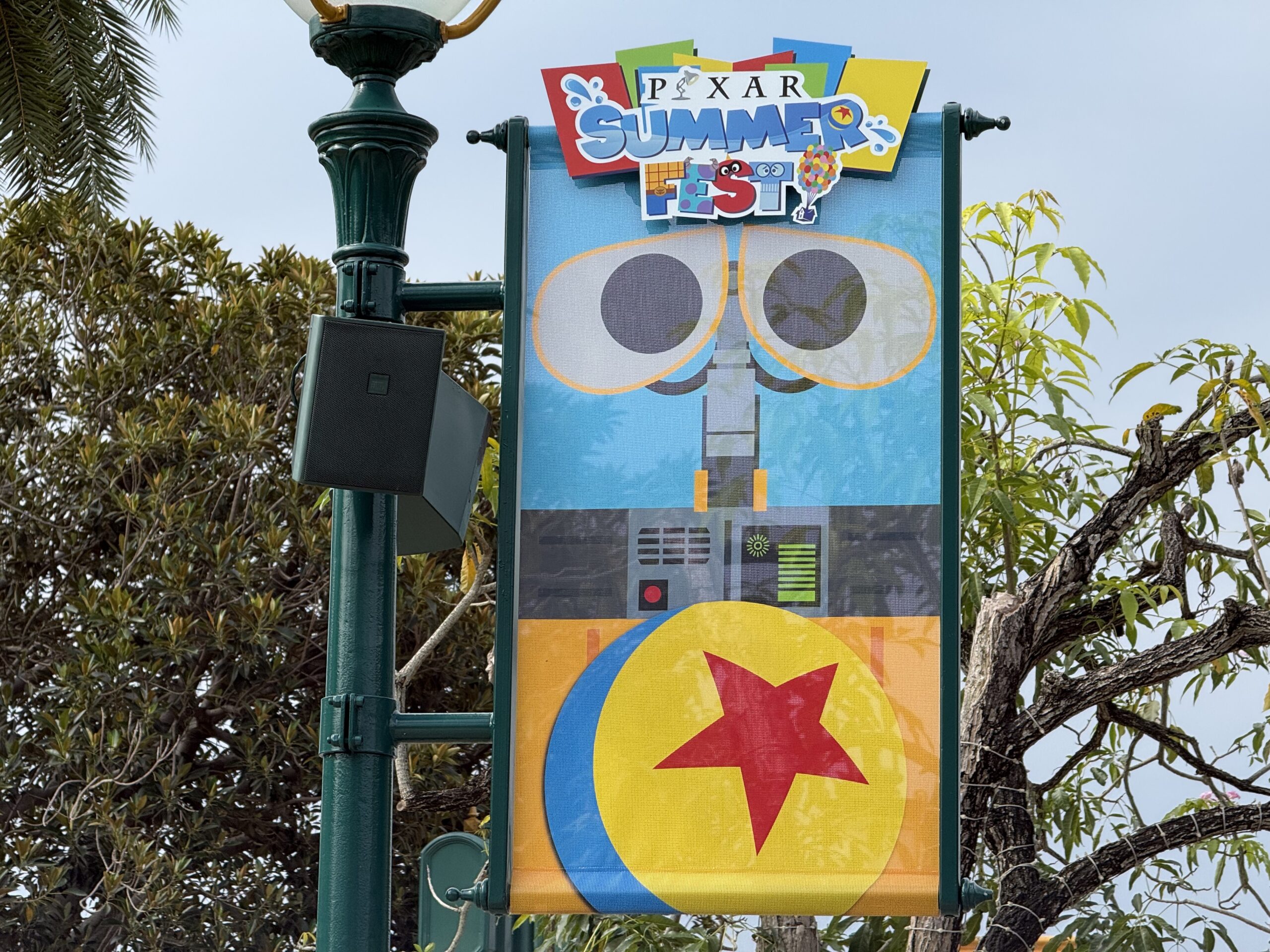 The walkway to the park entrance is lined with banners featuring Pixar characters and the Pixar Summer Fest logo.