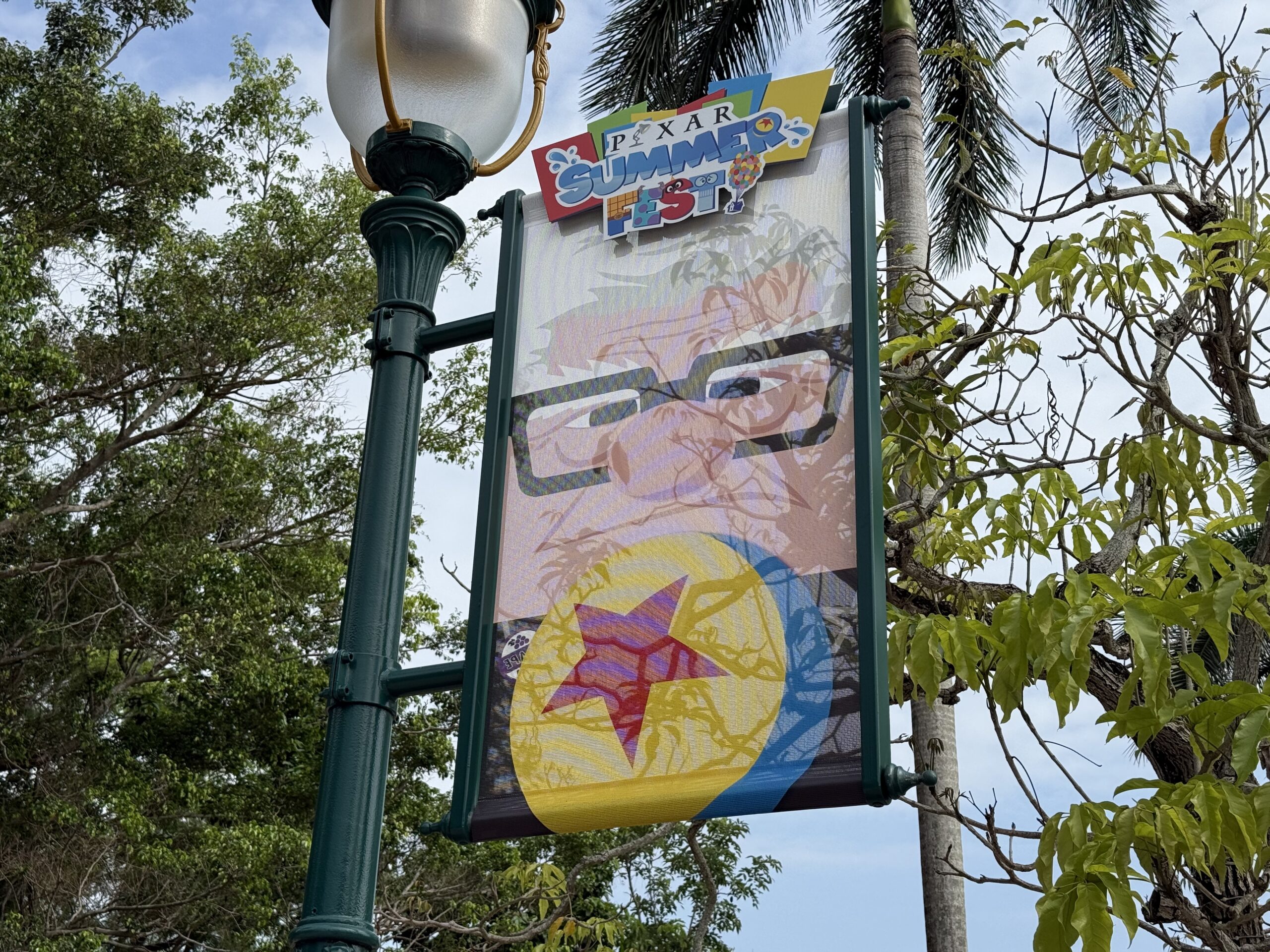 The walkway to the park entrance is lined with banners featuring Pixar characters and the Pixar Summer Fest logo.