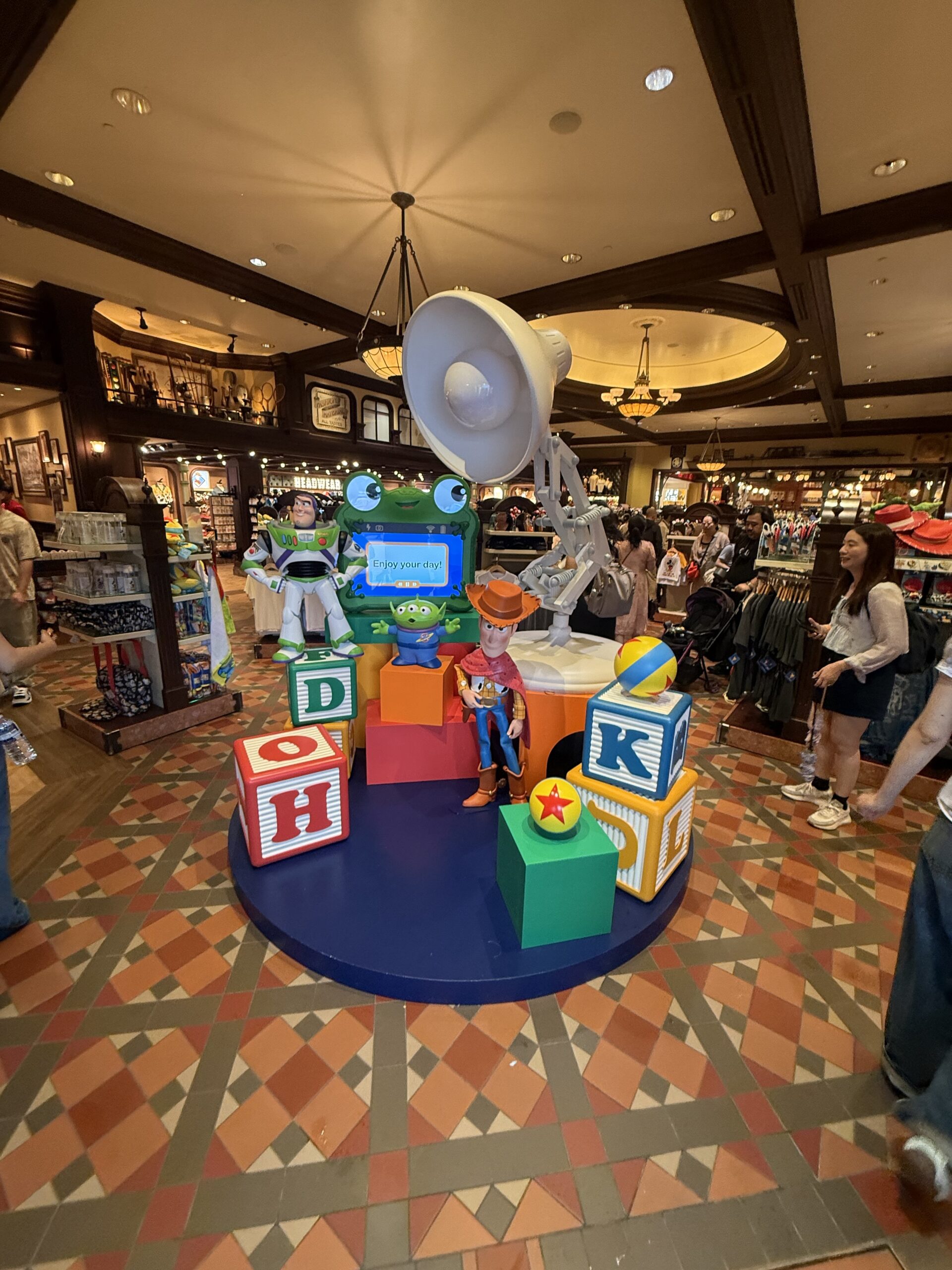 The Emporium is a display with another big Luxo Jr. leaning over other oversized toys: Lilypad from the new Toy Story 5, Buzz and a Little Green Alien, and Woody with his bandanna poncho. A couple of Pixar balls sit on toy blocks, which have the letters HKDL (Hong Kong Disneyland) facing forward.