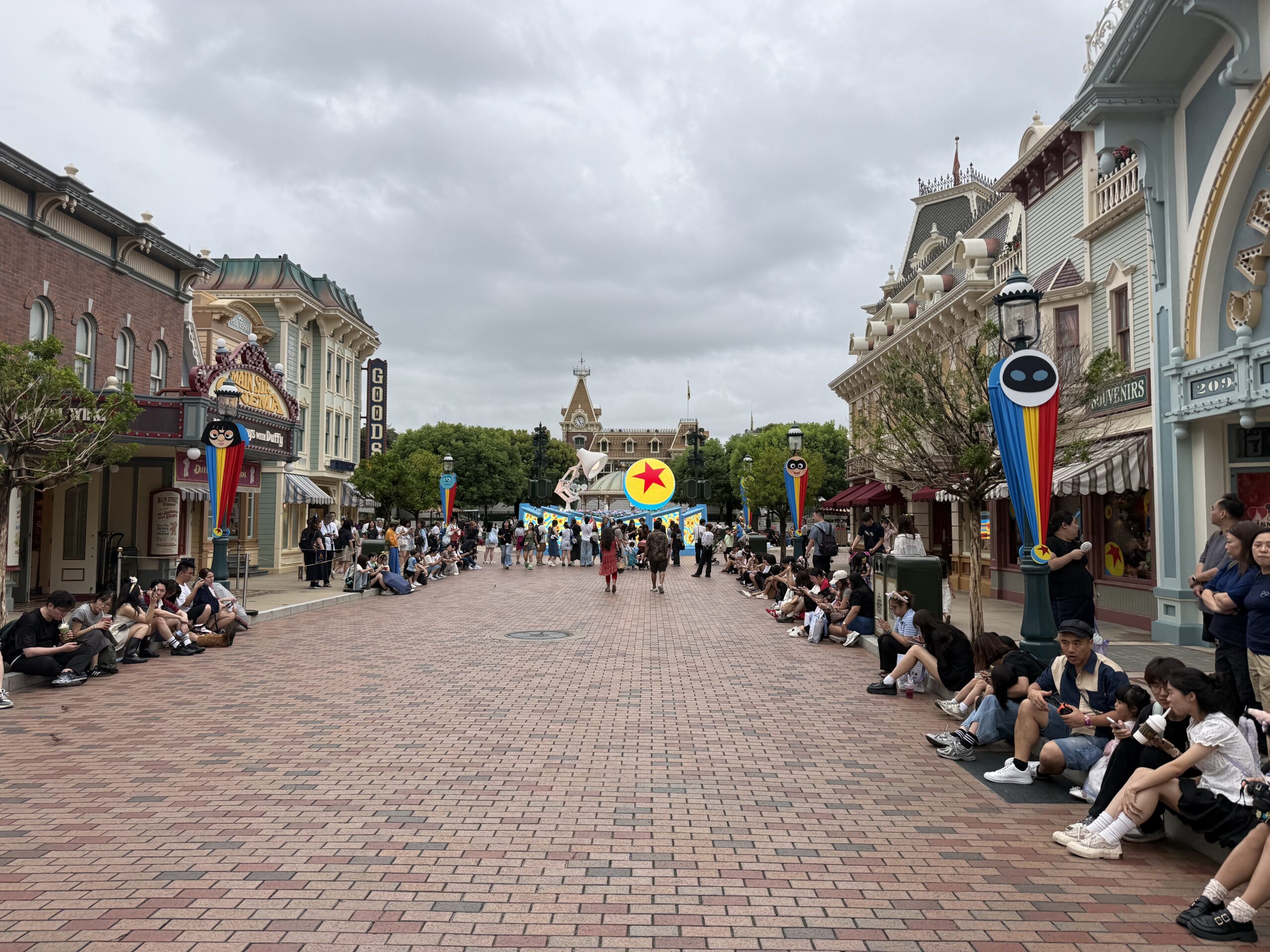 The Main Street lampposts are decorated with red, yellow, and blue striped banners. They are secured at the top with round character faces and at the bottom with a small Pixar ball element.