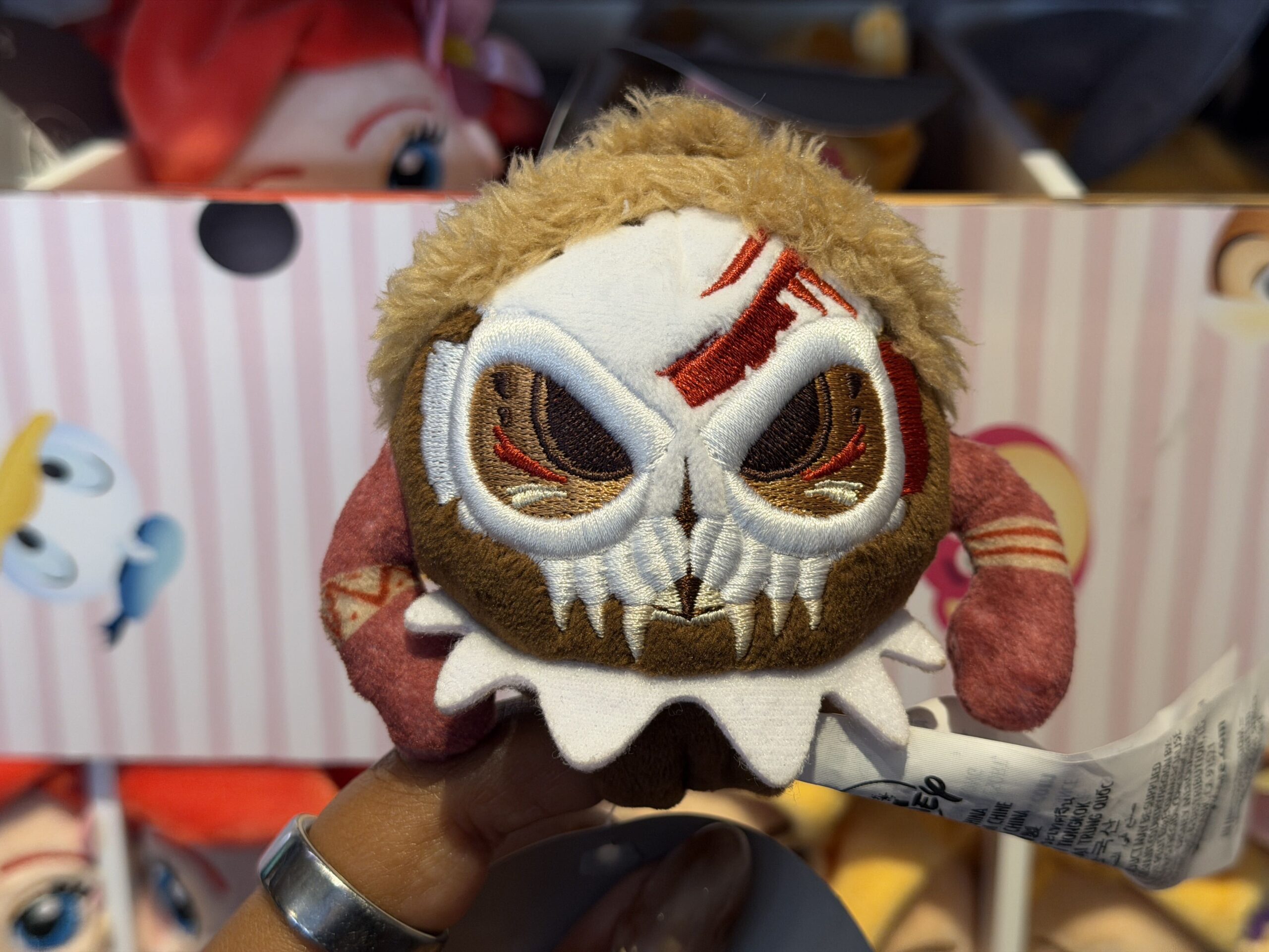 This menacing Kakamora plush shows the full body of the tiny coconutty villain, not just its head like the other two plush above. The Kakamora's arms stick out from either side of its body, and it has a skull over its face with embroidered detailing.