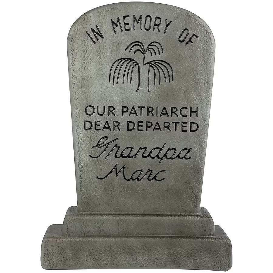 This tombstone reads, "In memory of our patriarch, dear departed Grandpa Marc." It's two feet tall with a gray stone-like finish. It can be used indoors or outdoors.