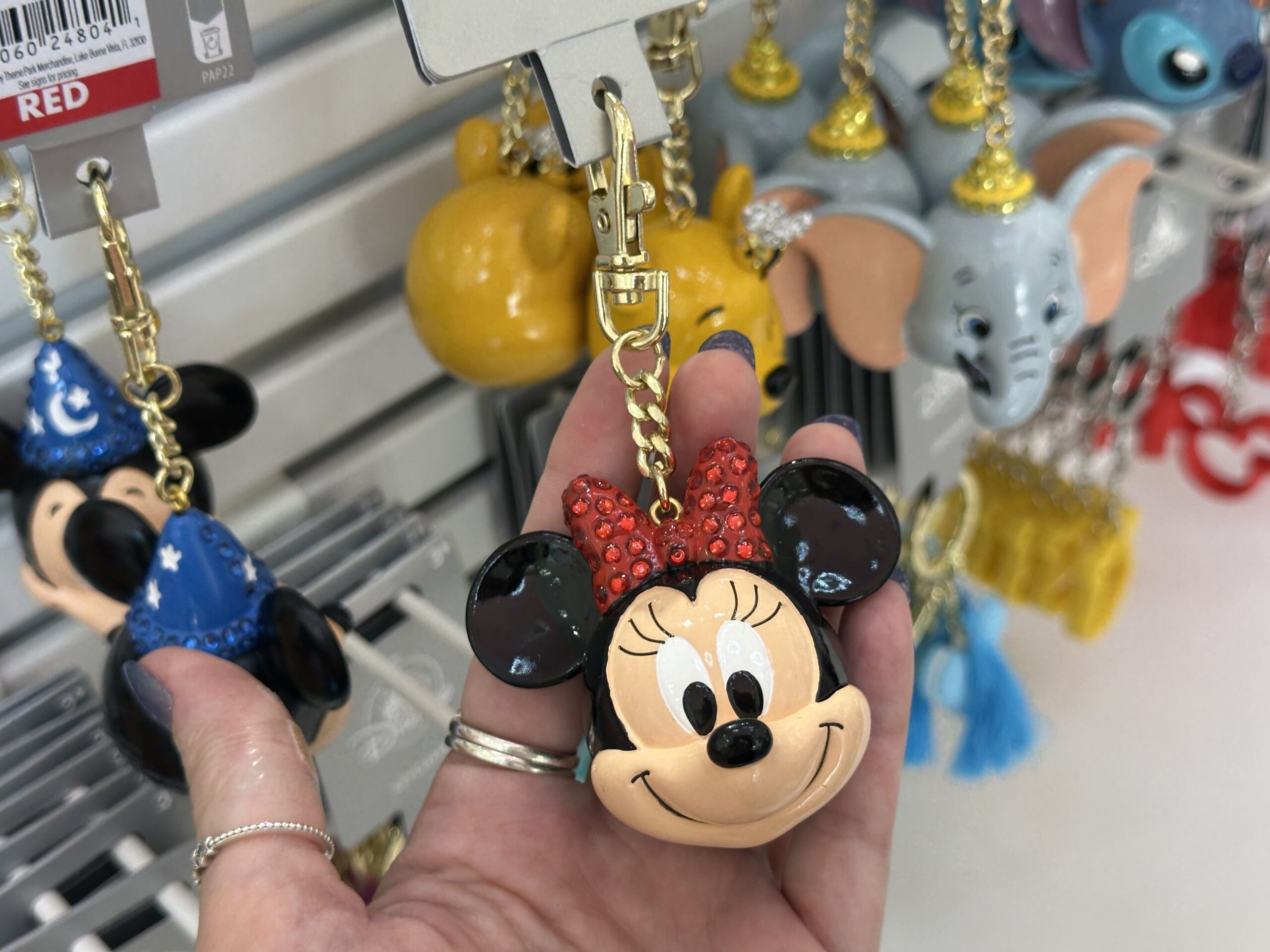 The next keychain is sculpted to look like the smiling head of Minnie Mouse. She is wearing a red bow on top that is studded with red gems.