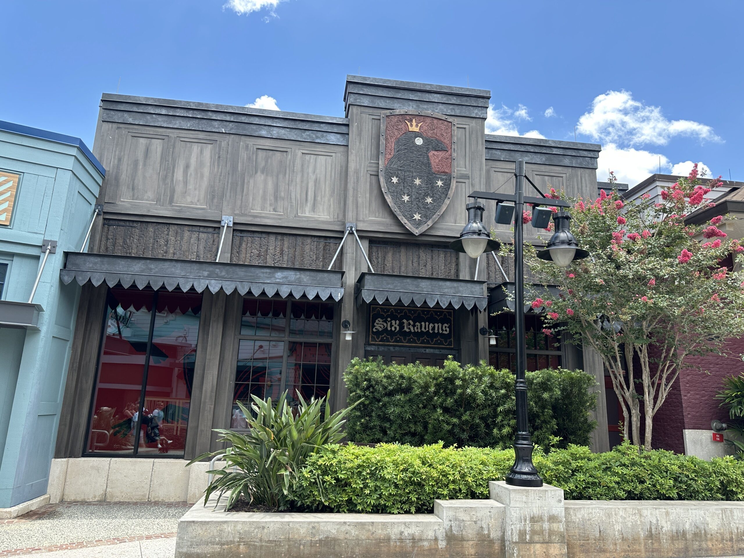 In a similar aesthetic style to Gideon's Bakehouse, Six Ravens has a darker exterior wood with similarly themed signage.