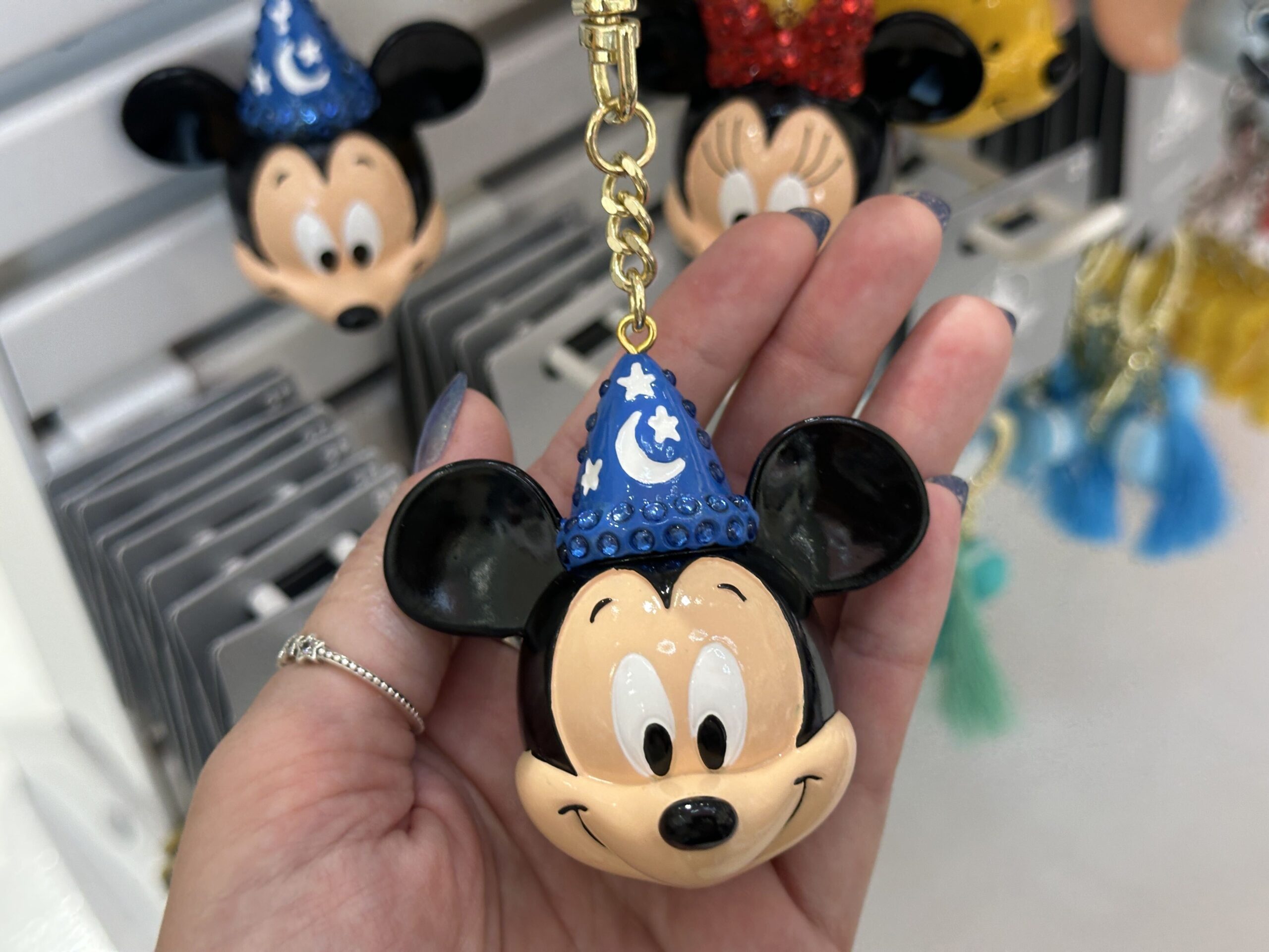Mickey is shown wearing his sorcerer's hat. The hat is navy blue with white painted stars and a crescent moon. Along the sides and brim of the hat are matching blue gems.
