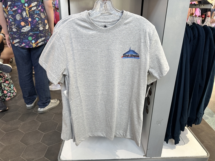 The heather gray T-shirt has the park's Magic Kingdom text logo and Tomorrowland above a Space Mountain ride vehicle on the back. The front has a small icon of the exterior of Space Mountain, the Magic Kingdom logo, and Tomorrowland text.