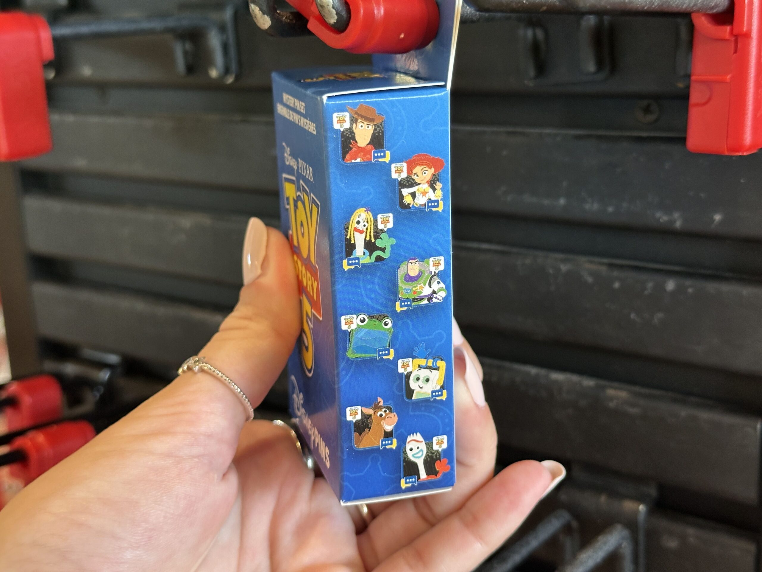 On the side of the box, we see the eight potential pins in the series. Each shows a different character seemingly in a chat bubble. One of the bottom corners has text typing icons, while one of the top corners shows a text bubble with the Toy Story 5 title image in it.