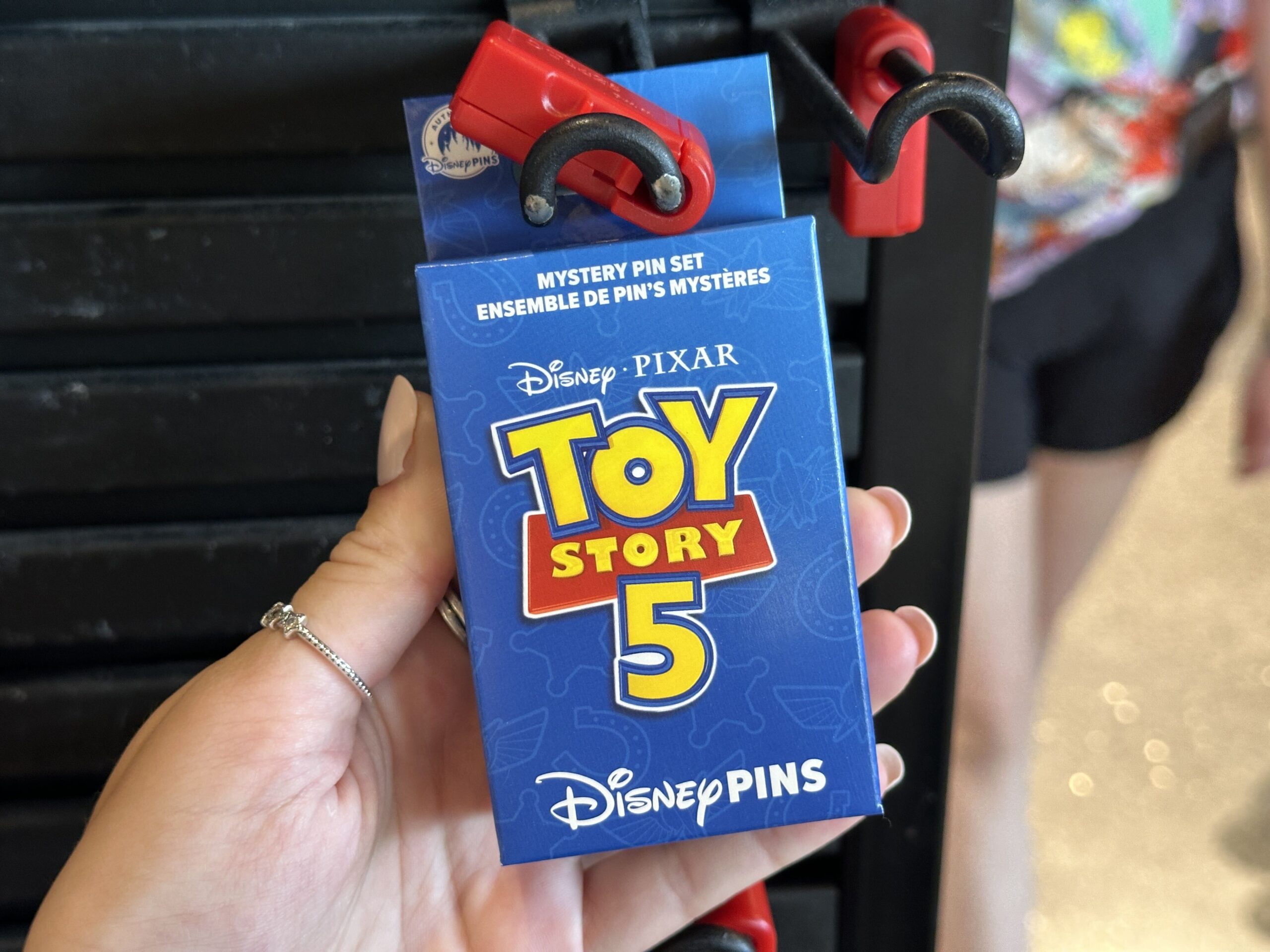 These mystery packs of pins come with two pins per pack, with eight total pins in the collection. The box is primarily navy blue with white outlines of Toy Story 5 iconography in the background and the film's title logo on the front.