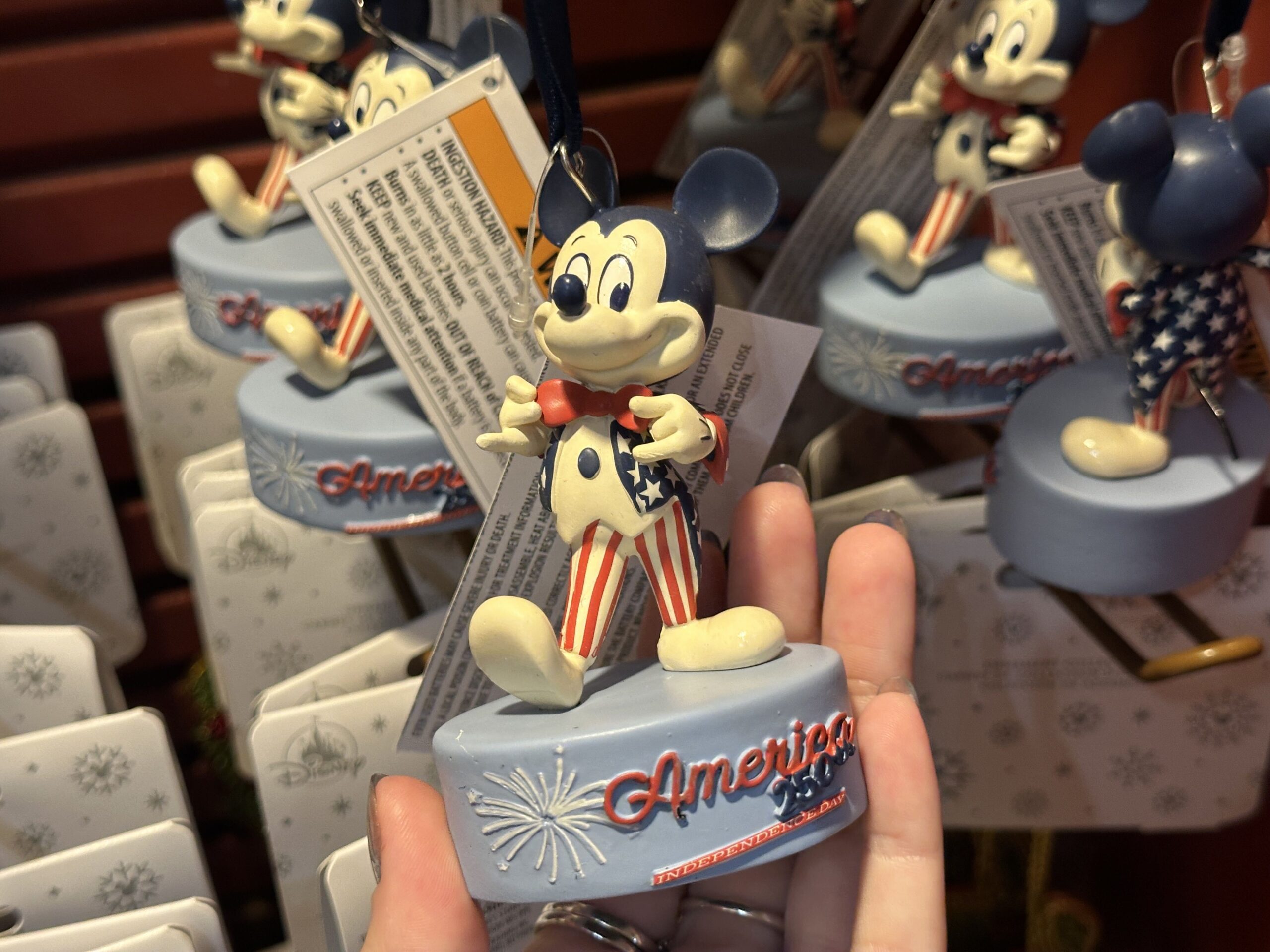 Honoring 250 years of the United States, this ornament depicts Mickey in a red, white, and blue tuxedo. His pants are striped, and his jacket is covered in stars. Instead of black ears, they are dark blue.