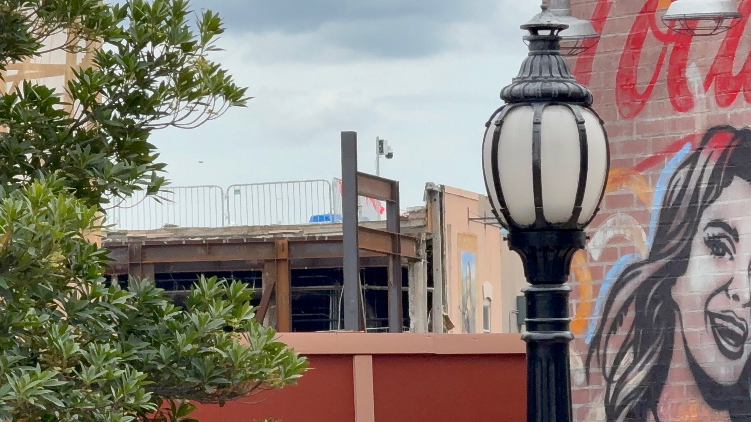 A set of I-beams jut out from the former Mama Melrose's facade. Most of the facade was stripped, but the Mona Lisa mural on one side still remains.
