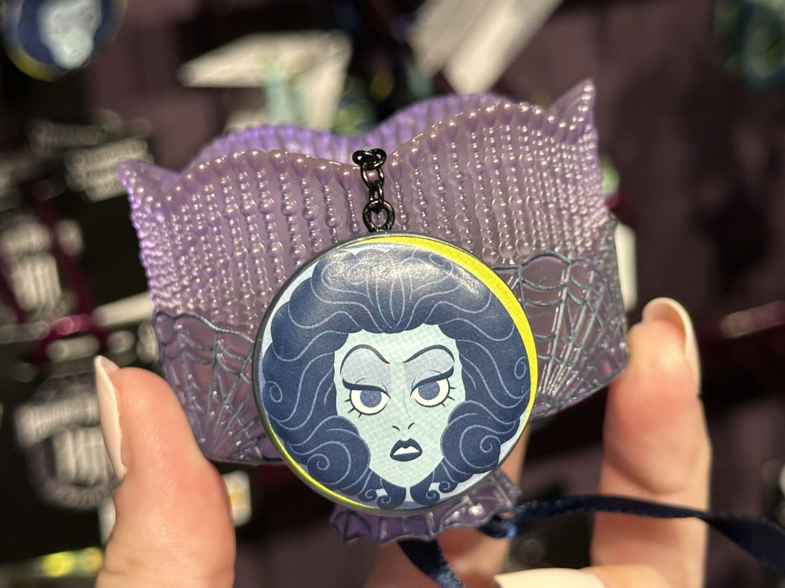 This ornament consists of a translucent "curtain" decorated with spiderweb designs. A circular charm of Madame Leota's face in her crystal ball dangles below the curtain.