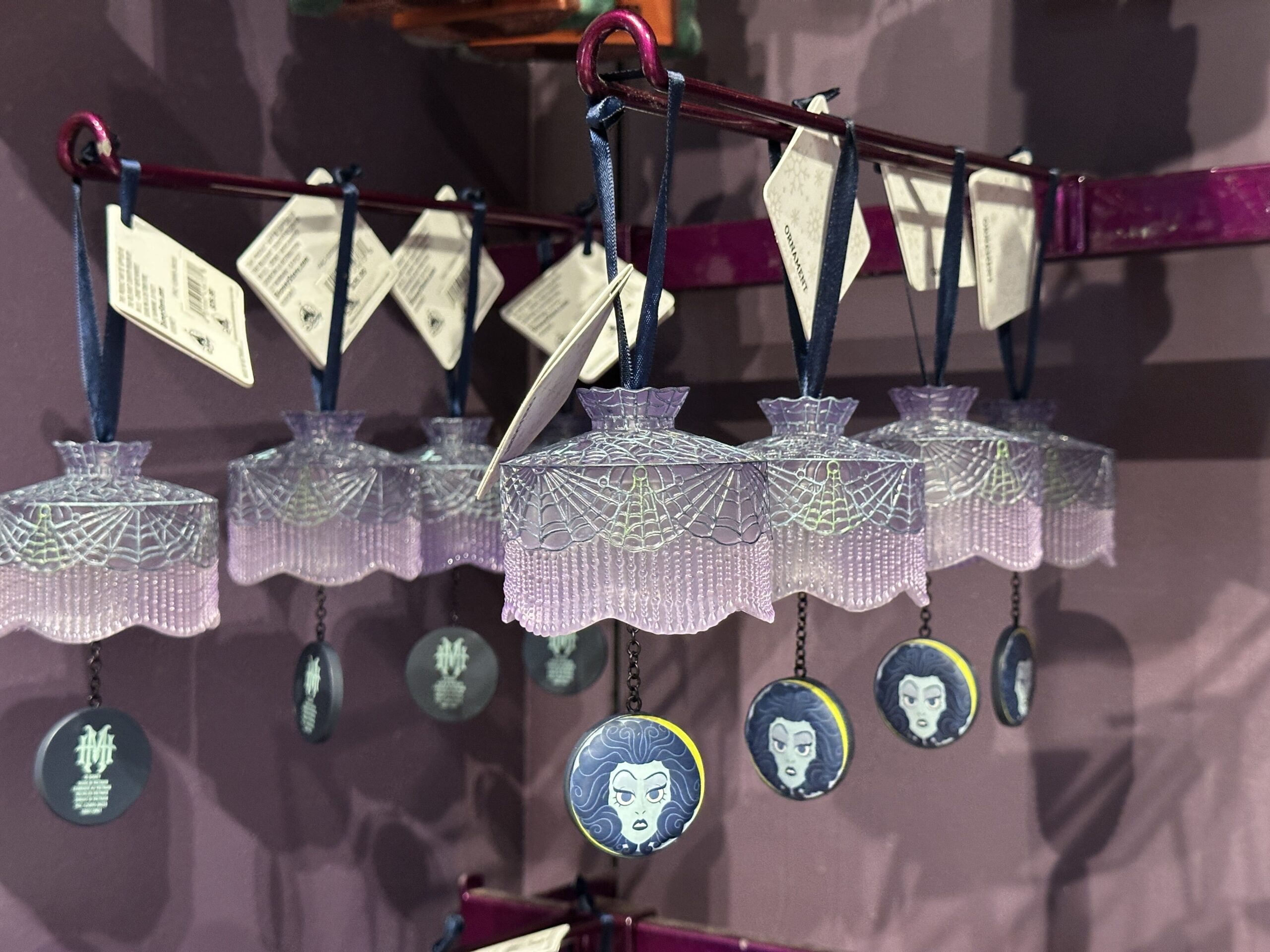This ornament consists of a translucent "curtain" decorated with spiderweb designs. A circular charm of Madame Leota's face in her crystal ball dangles below the curtain.