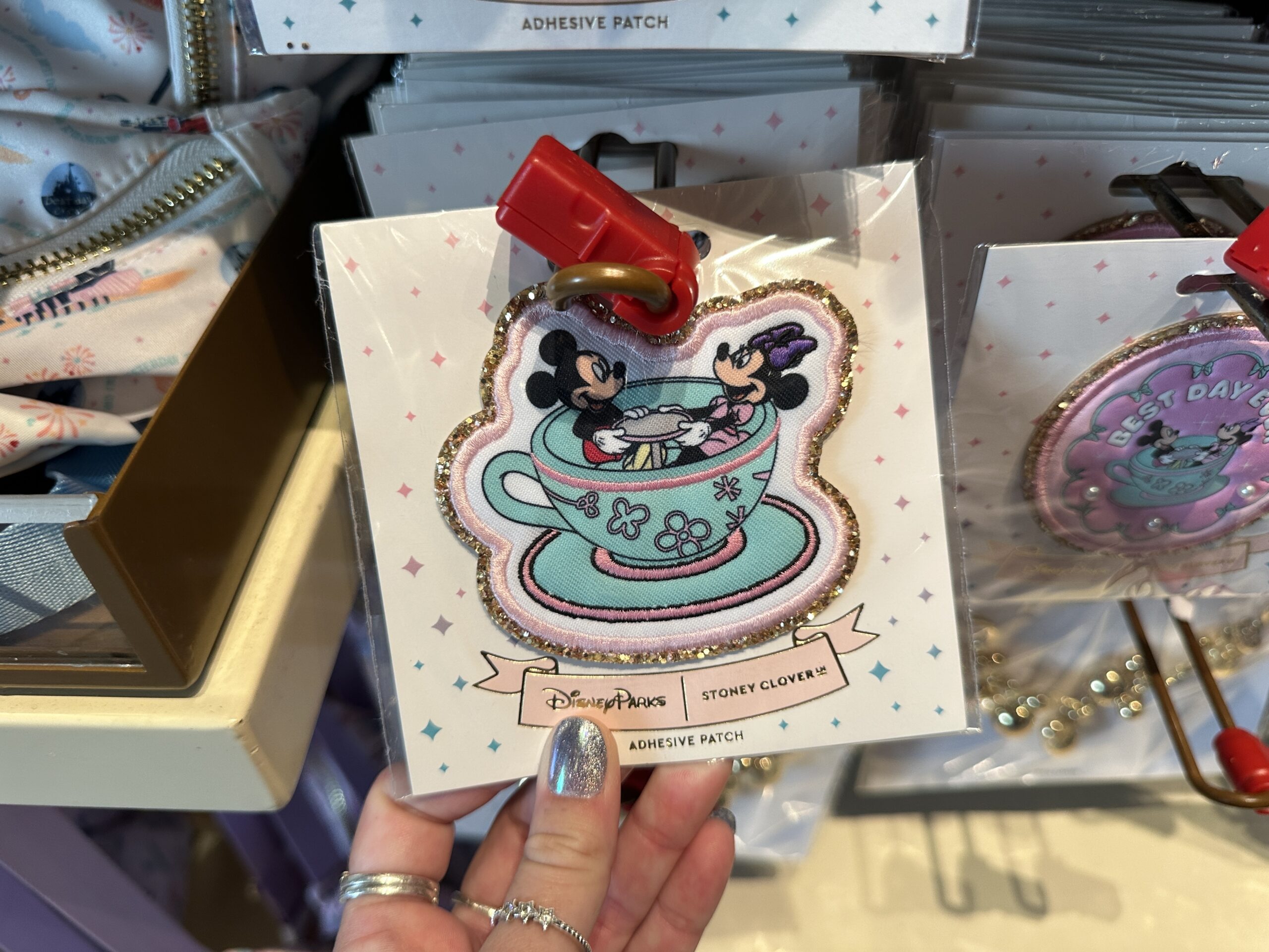 Mickey and Minnie are pictured spinning in an aqua-colored tea cup with pink embroidered edges. Each patch has a gold sequined border.