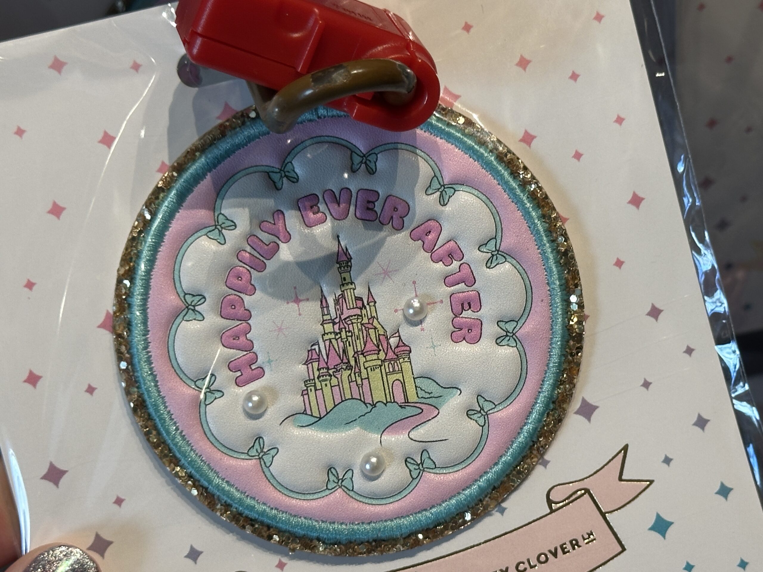 Another circular patch features the castle in shades of pink and yellow against a white background. "Happily Ever After" is in pink lettering. Like the other circular patch, it has three pearls.