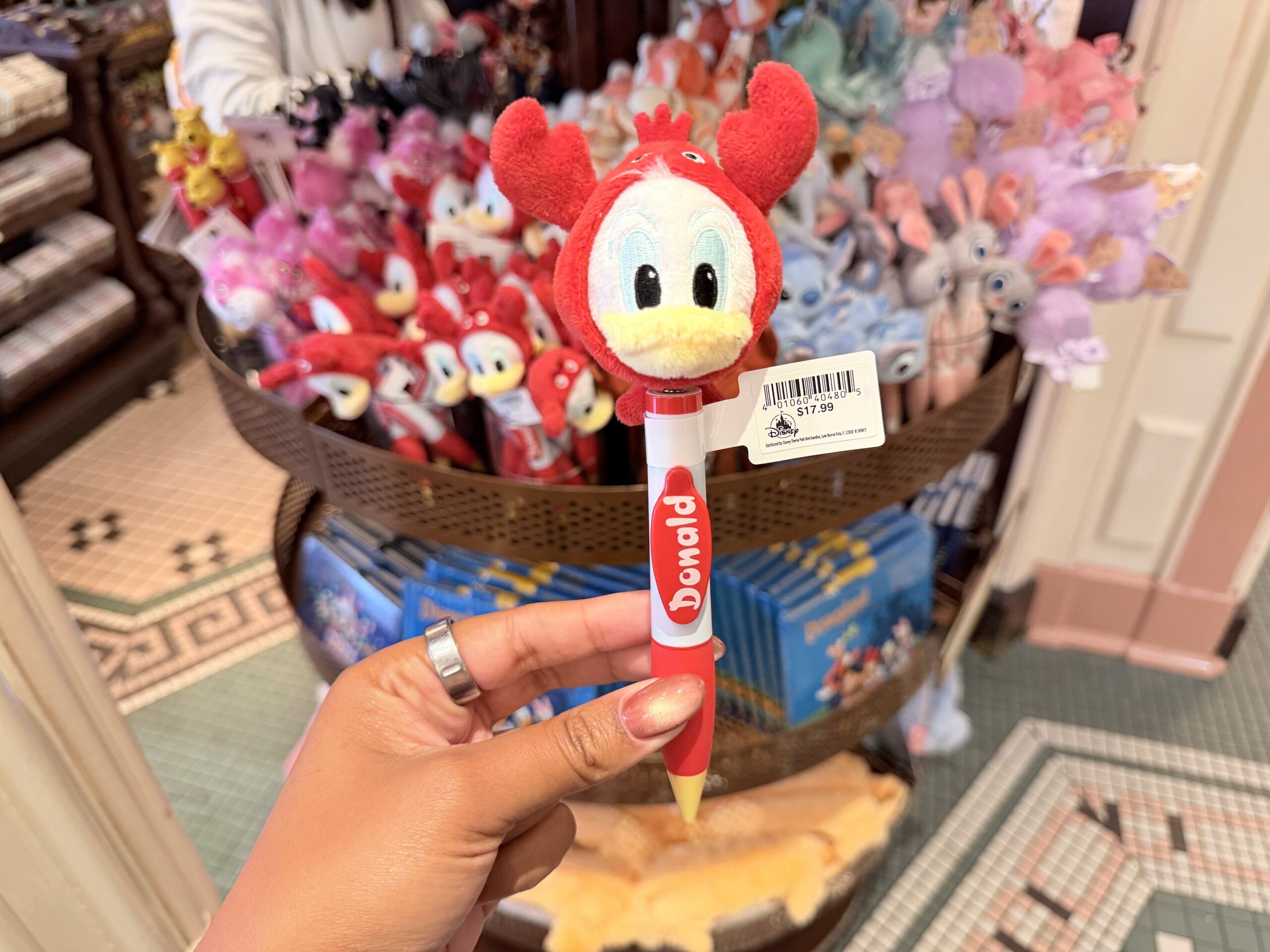 The Donald Duck pen features a plush Donald head in a bright red lobster costume. The topper includes Donald’s face, yellow bill, blue eyes, and red character details around the head.