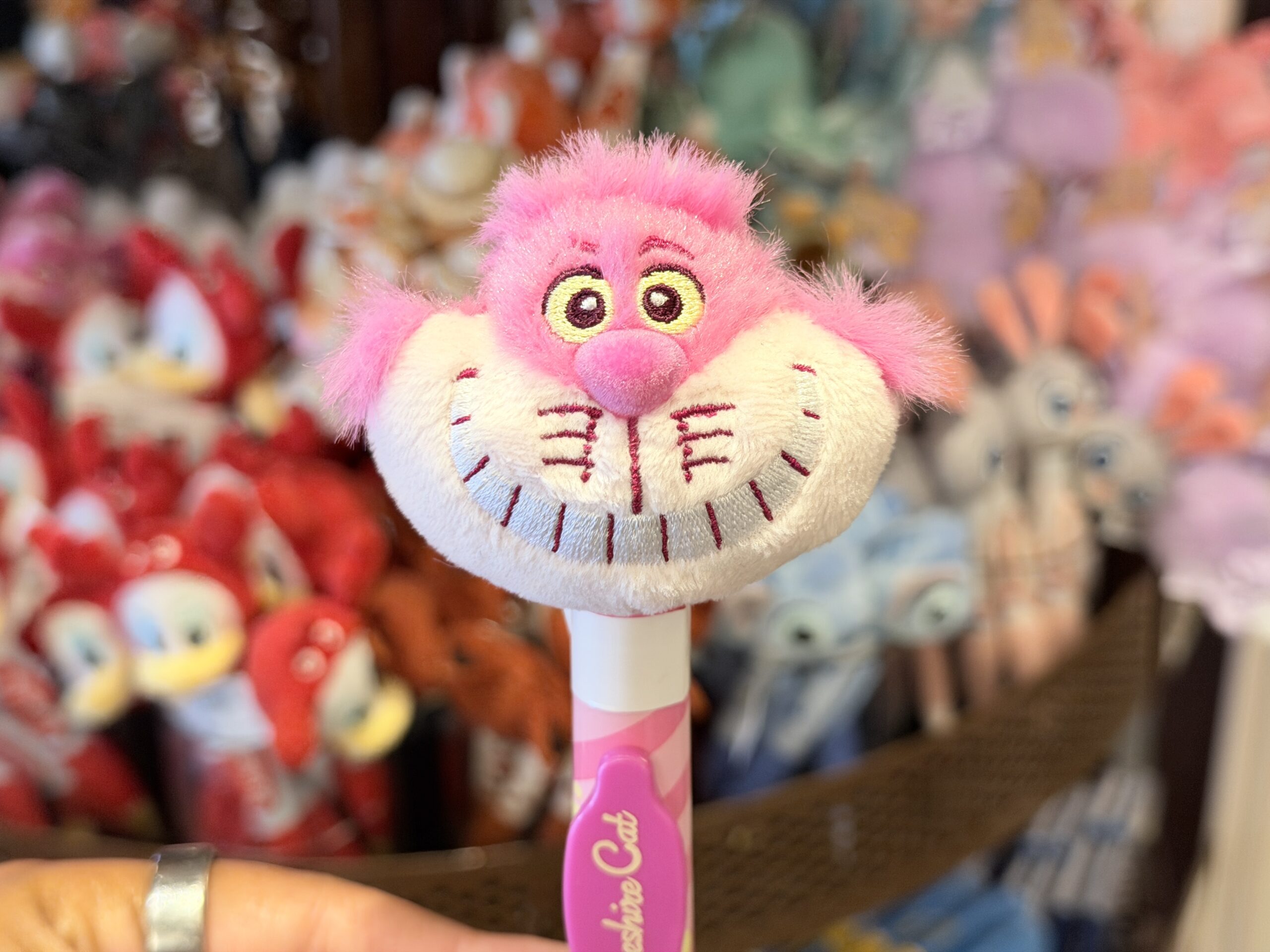 The barrel continues the pink theme with striped artwork and a darker pink nameplate reading “Cheshire Cat.” The pen has a light pink lower section and white tip.