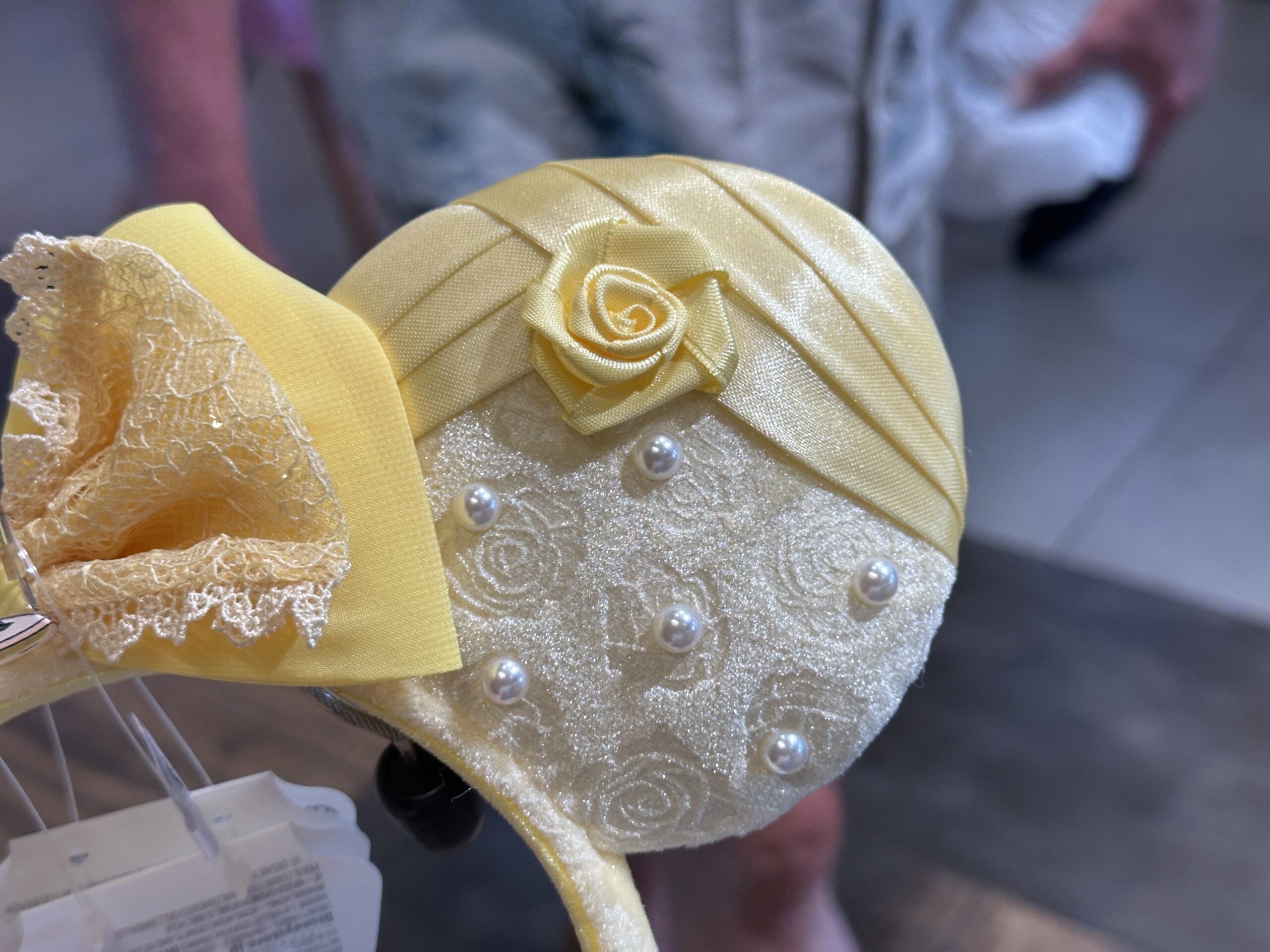 Each of the ears also has two layers. The top layer is a muted yellow satin with a matching fabric rose in the middle, a nod to the rouching in Belle's gown. The bottom layer is a lace-inspired velour fabric with roses in it as well as faux pearls attached.