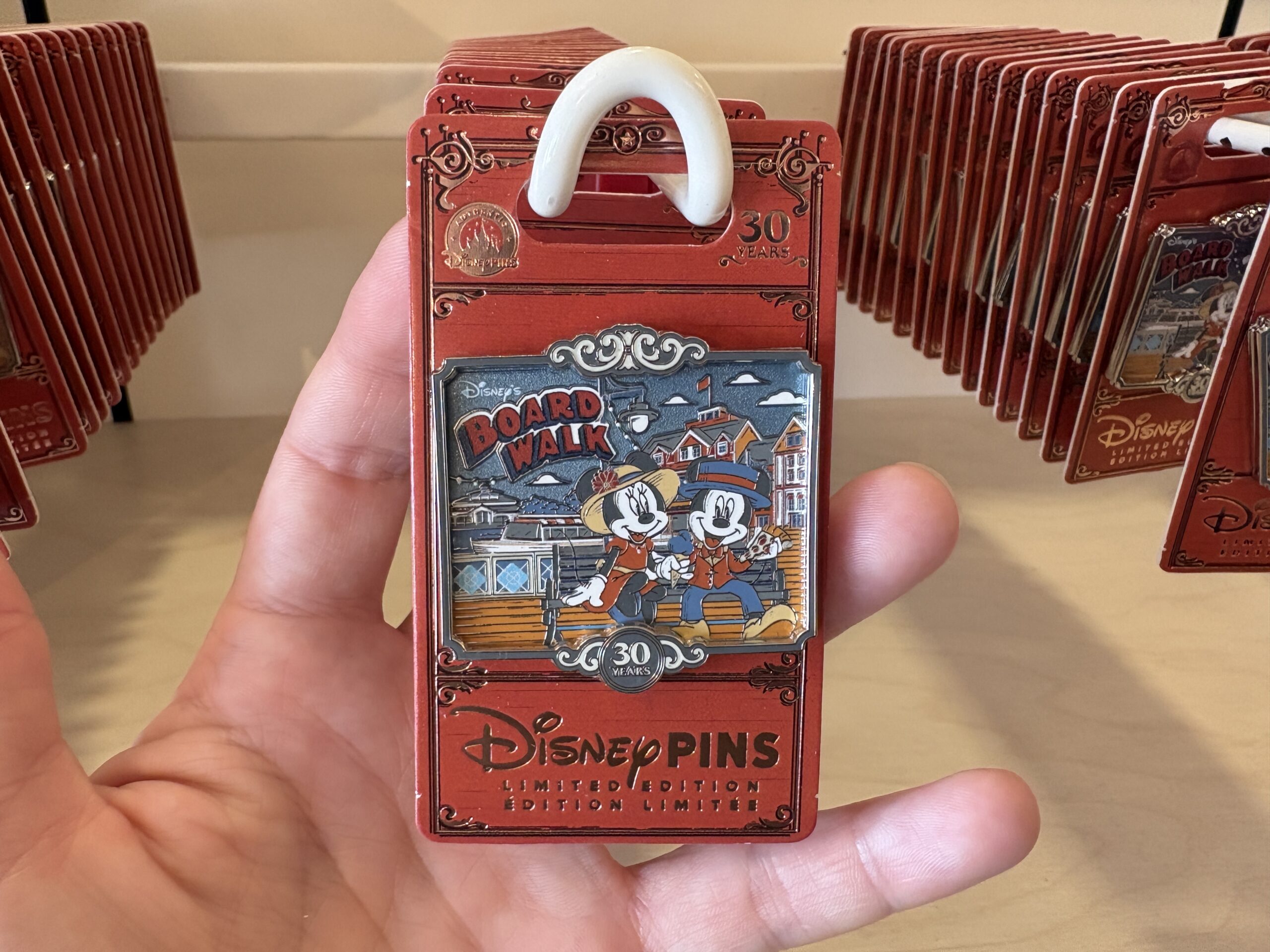 The pin shows Minnie and Mickey in their casual boardwalk leisure attire sitting on a bench. Minnie is eating a blue ice cream cone and Mickey has a slice of pizza. Behind them are various buildings from the resort property. A small "30 years" emblem is at the bottom.