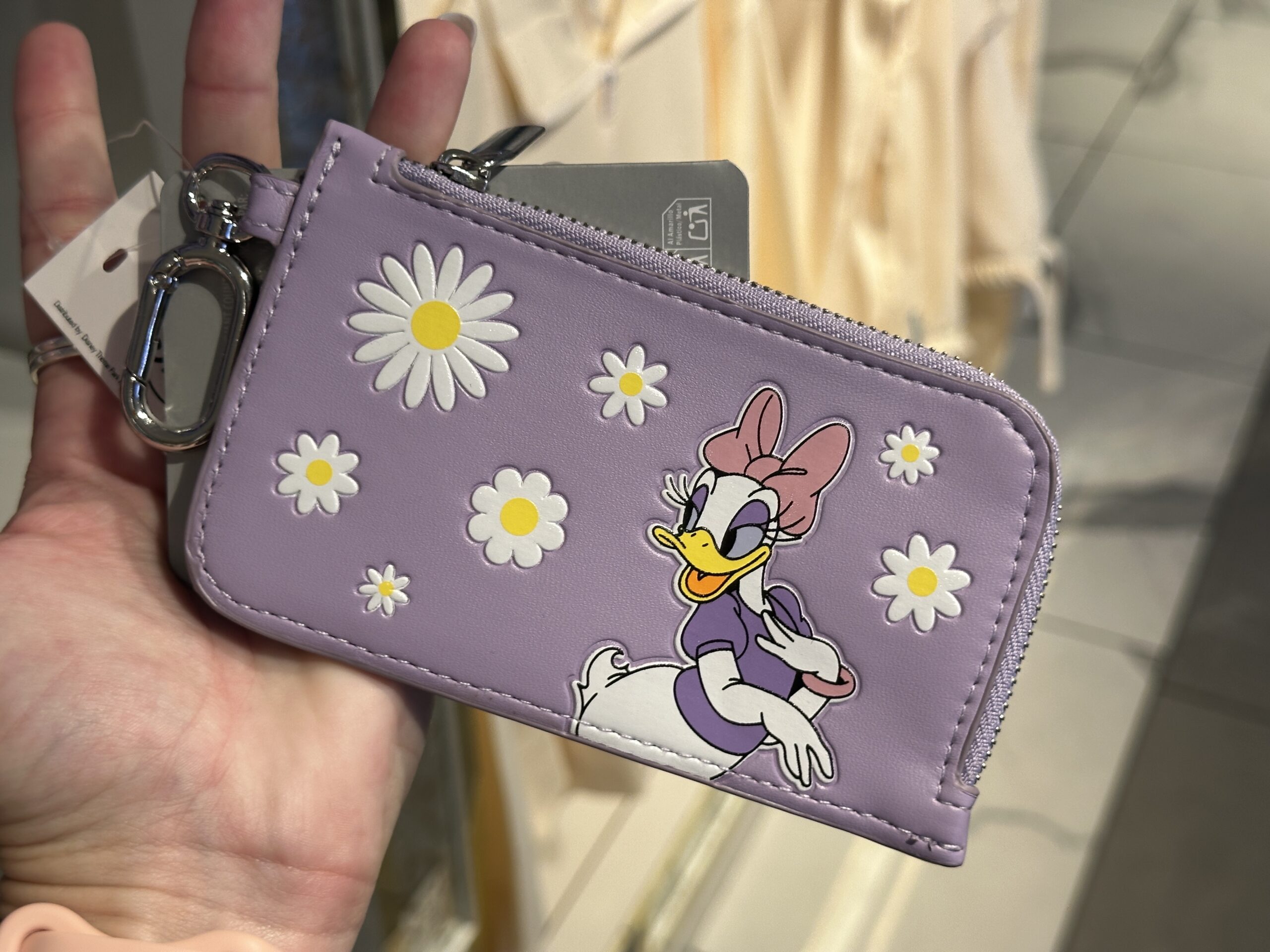 In lavender, this keychain wallet has colorful daisy flowers on it as well as Daisy Duck herself. The back of the wallet just has the repeating daisy flower pattern as well as two card slots and an ID card section.