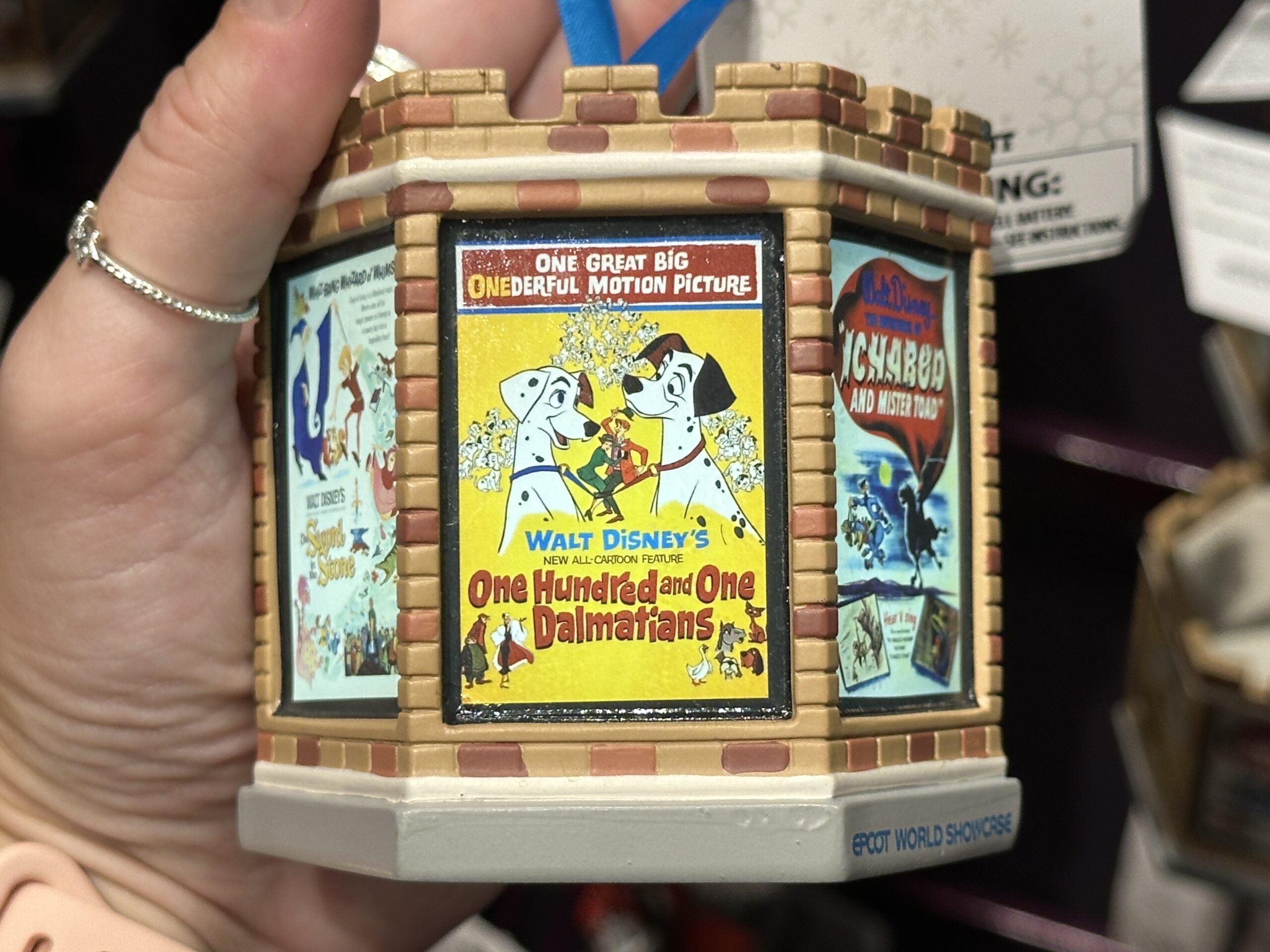 This six-sided, light-up ornament celebrates classic Disney films that took place in England. Each side has a different vintage poster from the film. These include Peter Pan, The Sword in the Stone, One Hundred and One Dalmatians, Icabod and Mister Toad, Alice in Wonderland, and Robin Hood. The ornament is designed like the top of a castle tower.