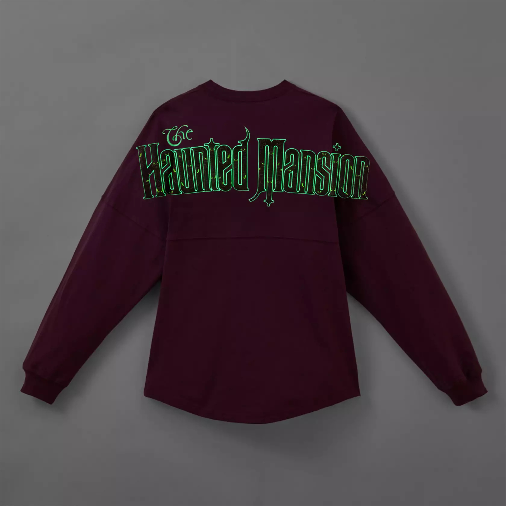 This purple cotton jersey features a section of the ride's famous damask wallpaper on the left chest with "The Haunted Mansion." Across the back is the ride's name in larger letters. The designs on the front and back both glow green in the dark.