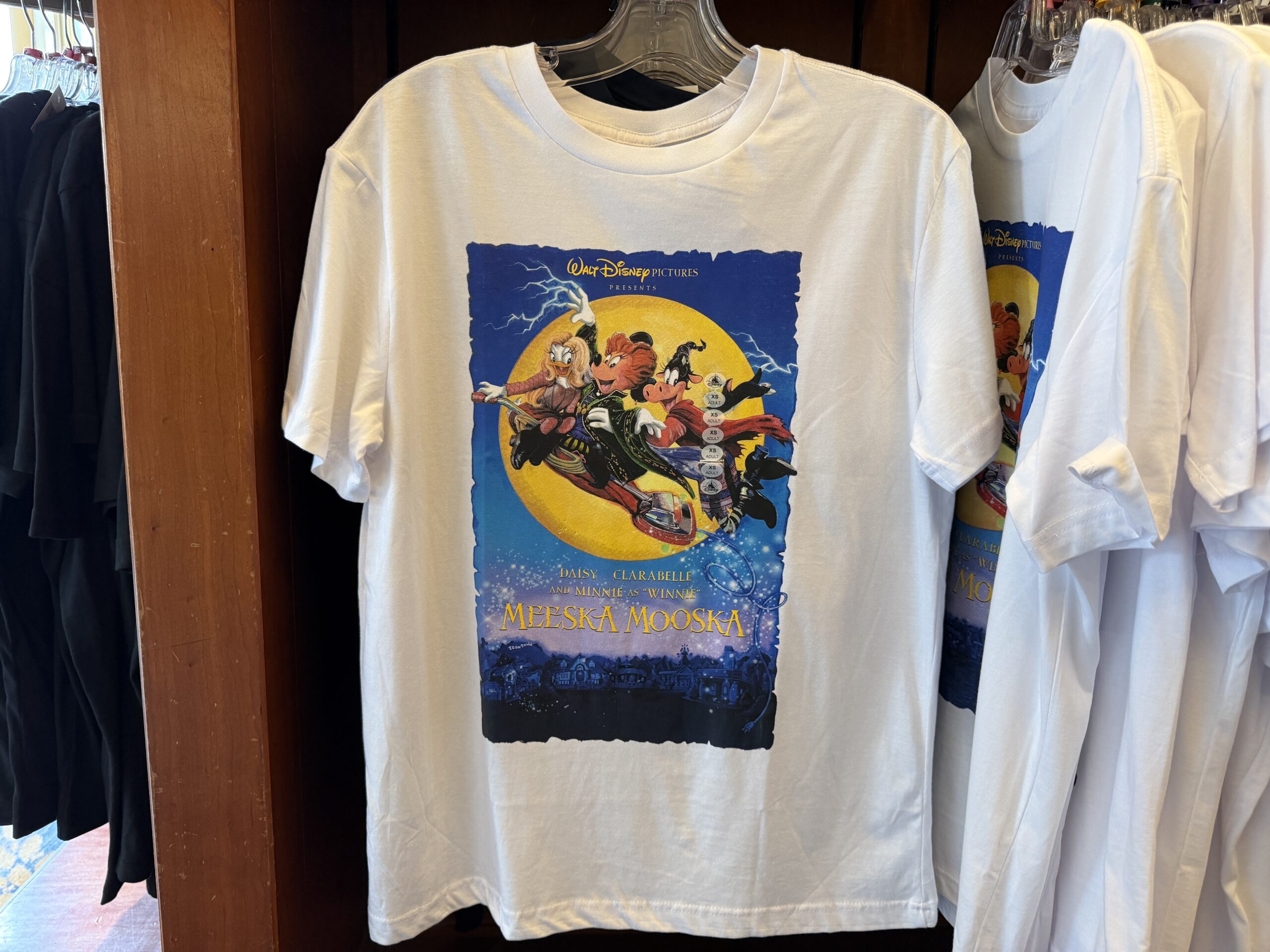 This white T-shirt is one for the Hocus Pocus fans. It parodies the three witches as Daisy, Minnie, and Clarabelle Cow on a fake version of the movie poster for the film titled “Meeska Mooska.” This poster is seen in Mickey and Minnie’s Runaway Railway at Disneyland.