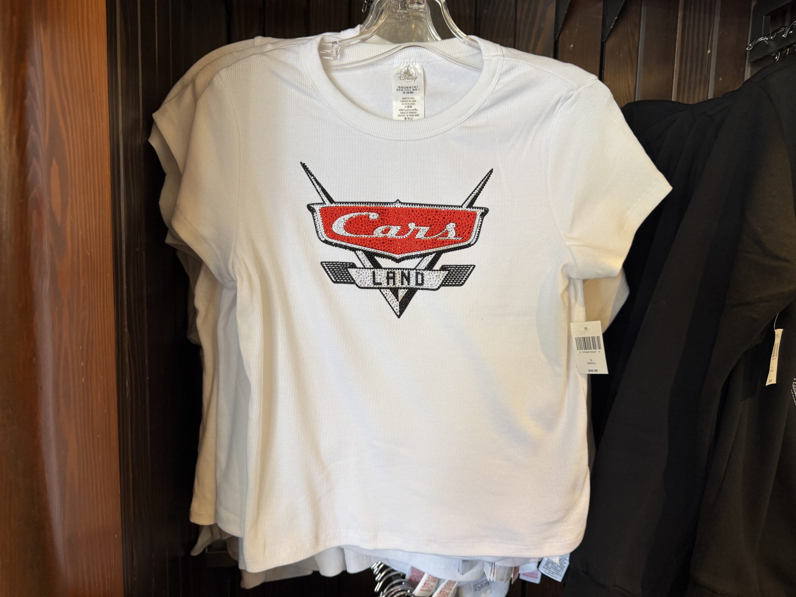 This white tee has a large bedazzled logo in the center of the chest. The back is plain.