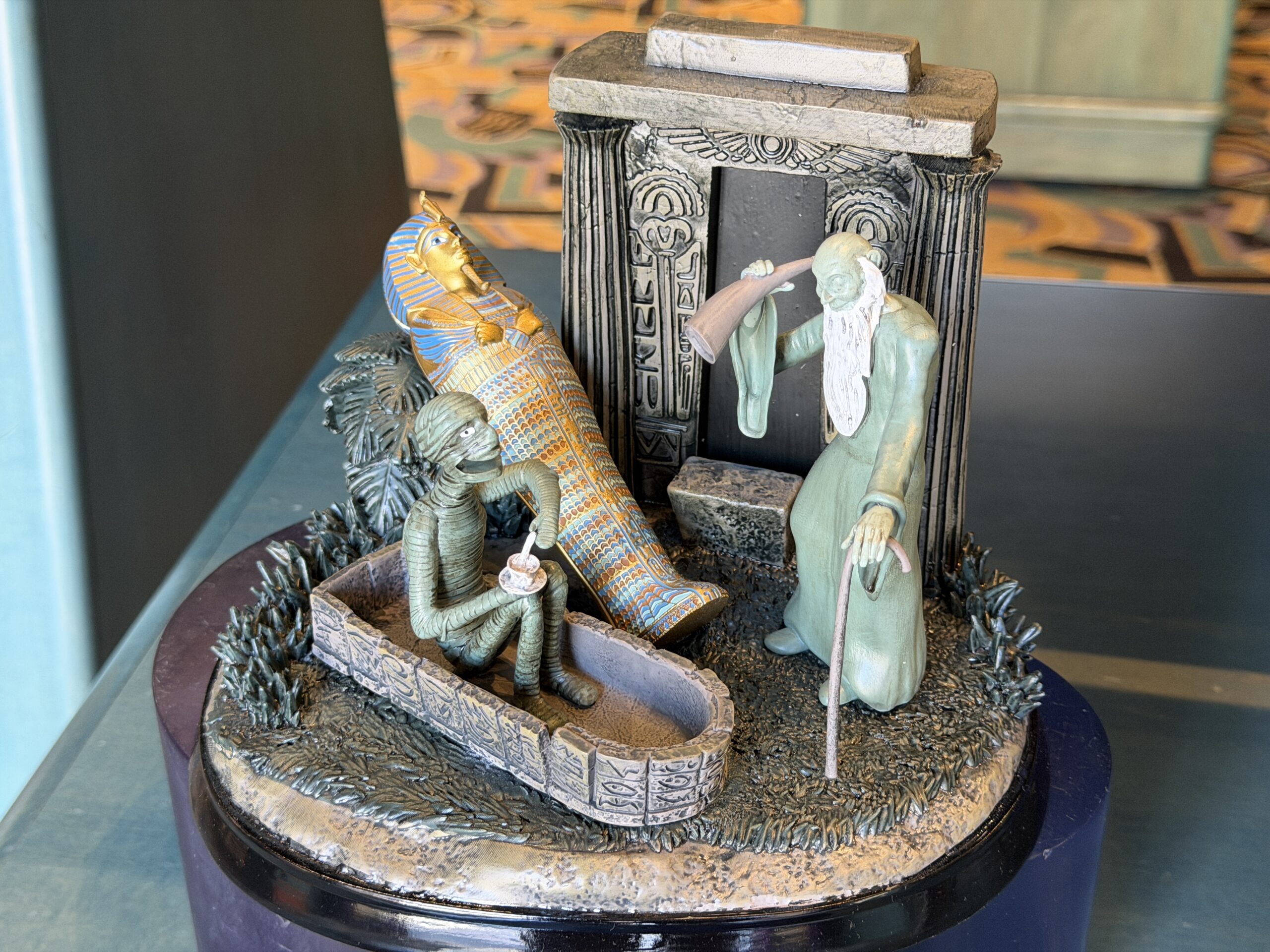 The musical figure shows the Deaf Ghost a.k.a. Father Time listening to the Mummy Prince Amenmose, who is enjoying a cup of tea. The intricate top of the Egyptian-style sarcophagus is in the background.