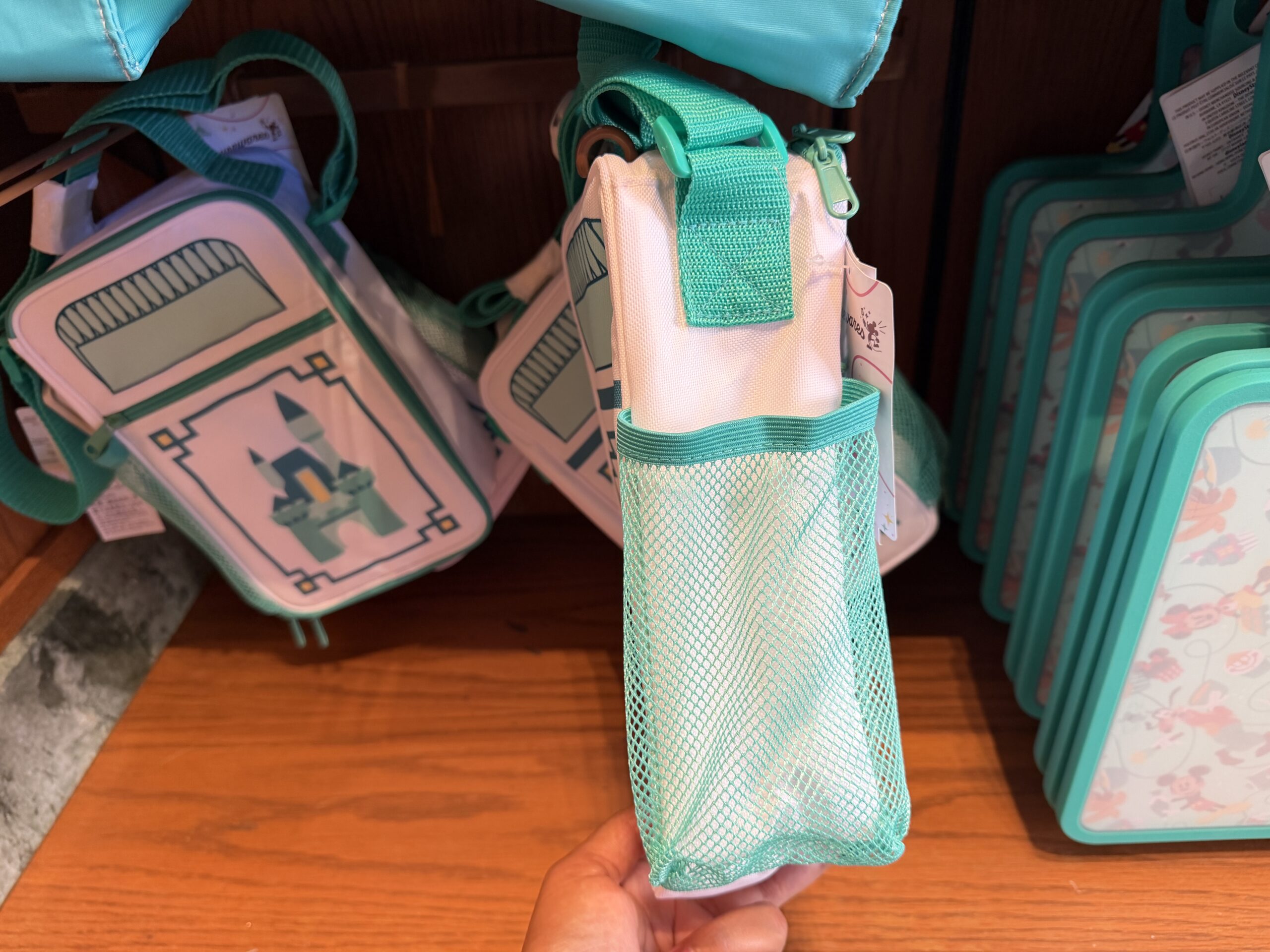 At Kingswell Shop in Disney California Adventure was this trash can-inspired lunch box. It has the classic Disney trash can shape in a white and teal color scheme. A simple Disney castle is on a small front zip pocket.