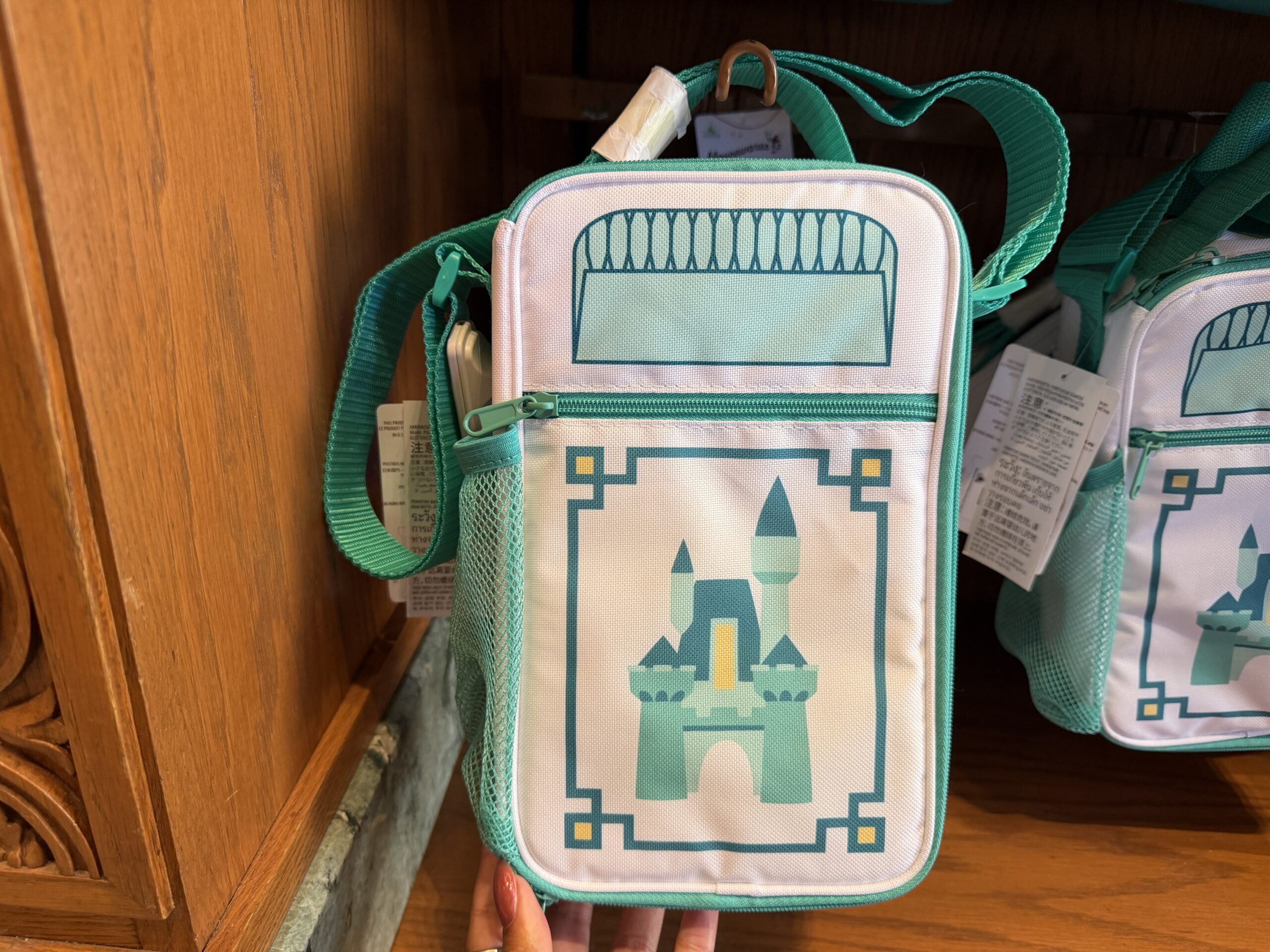 At Kingswell Shop in Disney California Adventure was this trash can-inspired lunch box. It has the classic Disney trash can shape in a white and teal color scheme. A simple Disney castle is on a small front zip pocket.