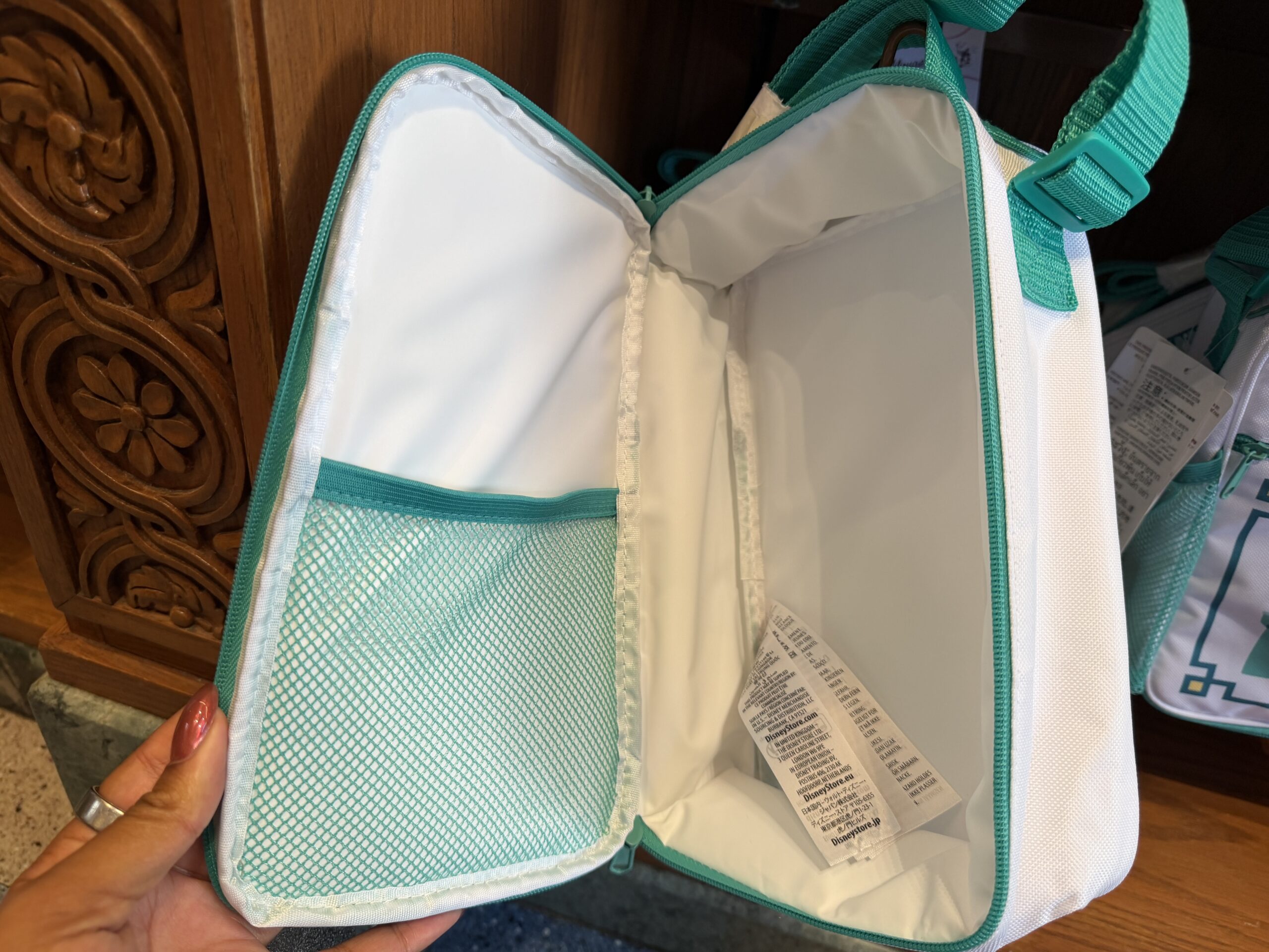 At Kingswell Shop in Disney California Adventure was this trash can-inspired lunch box. It has the classic Disney trash can shape in a white and teal color scheme. A simple Disney castle is on a small front zip pocket.