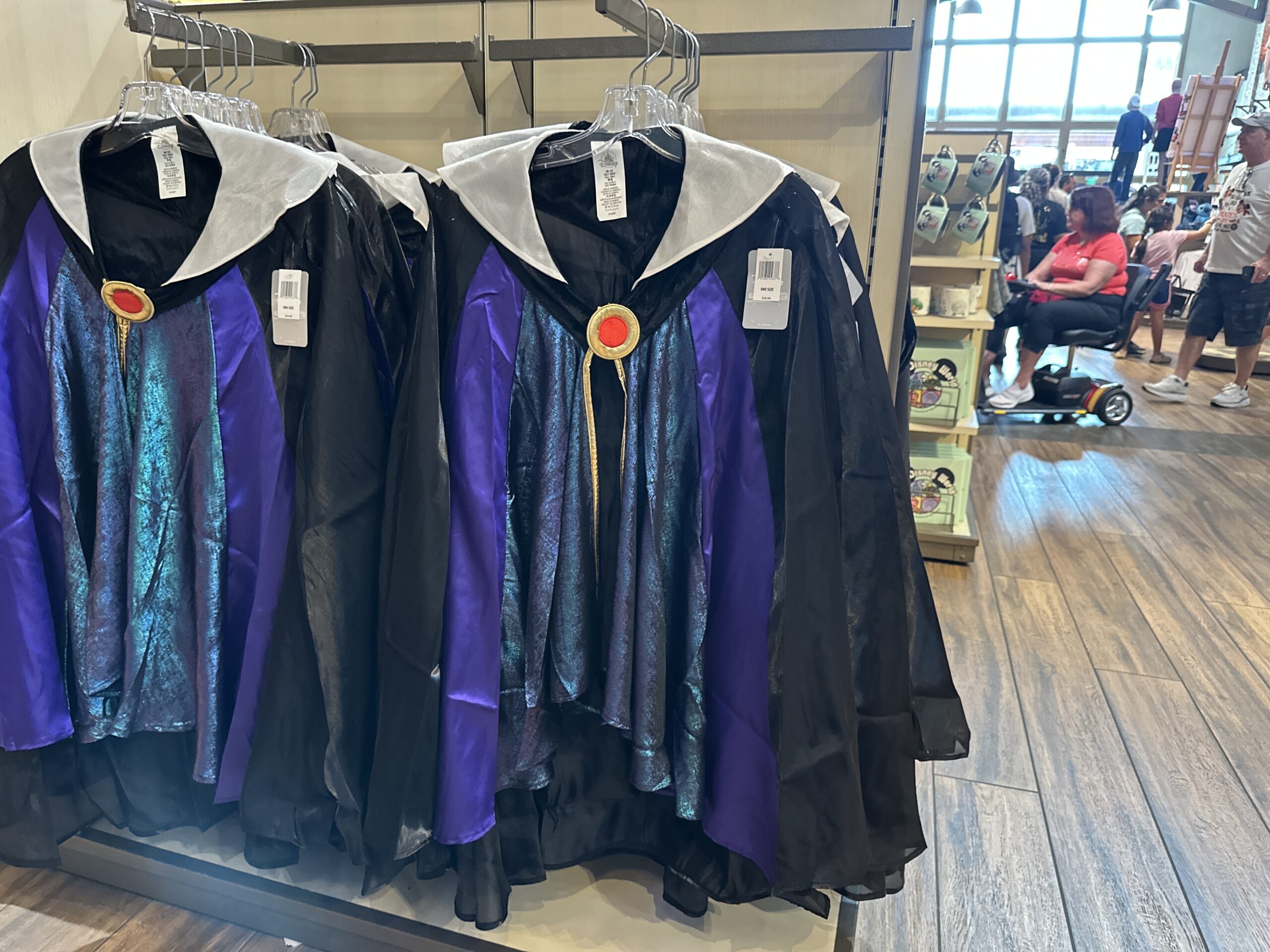 Dress up as the Evil Queen from Snow White in this costume. With a cape, this outfit top is primarily black with shimmery blue and purple details as well as the queen’s signature red and gold pendant and her pointy white collar.