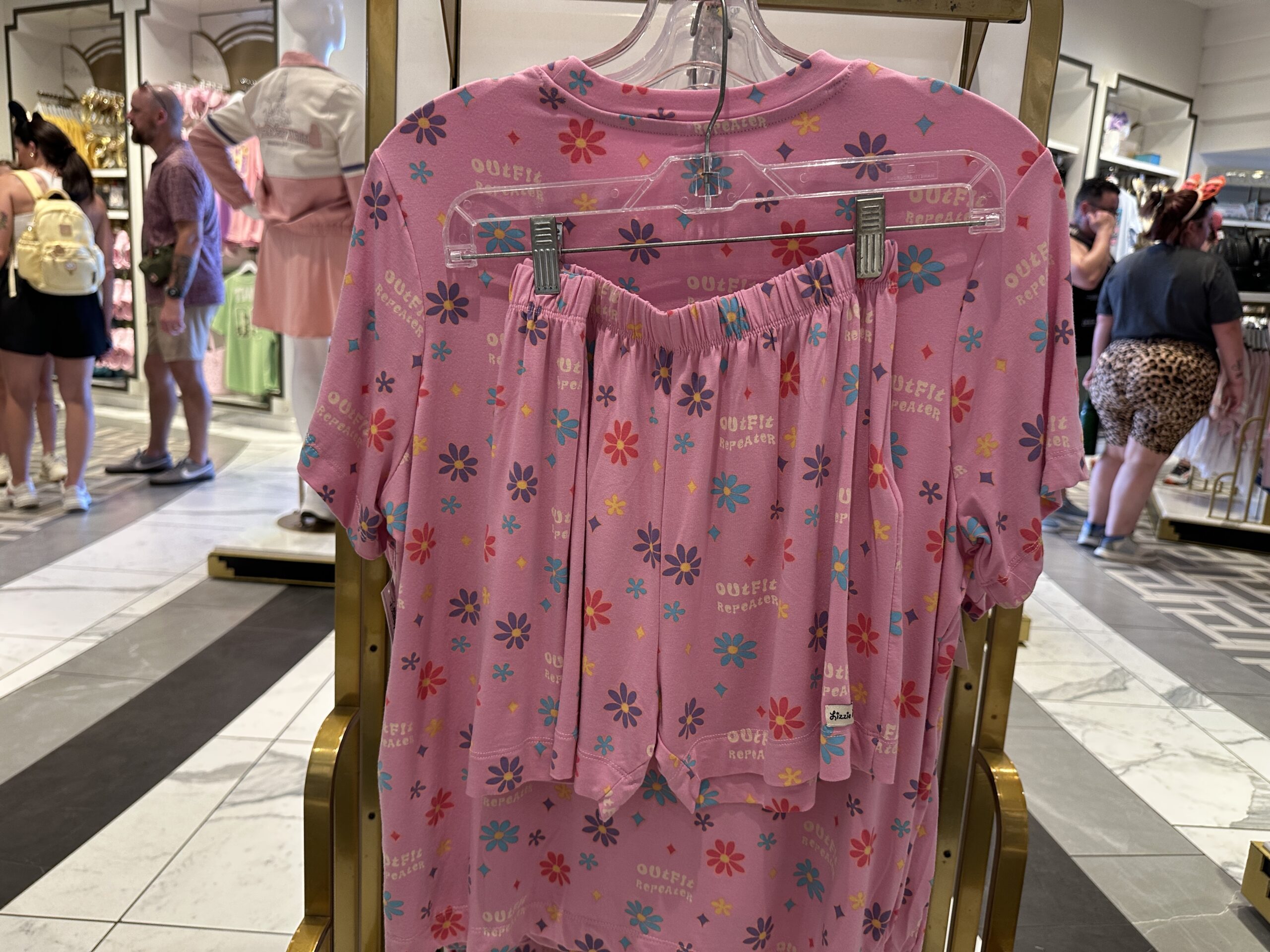 In a bright pink, this short-sleeved and shorts sleep set has blue, purple, yellow, and pink flowers and stars throughout. It also says "outfit repeater" and is themed to Lizzie McGuire.